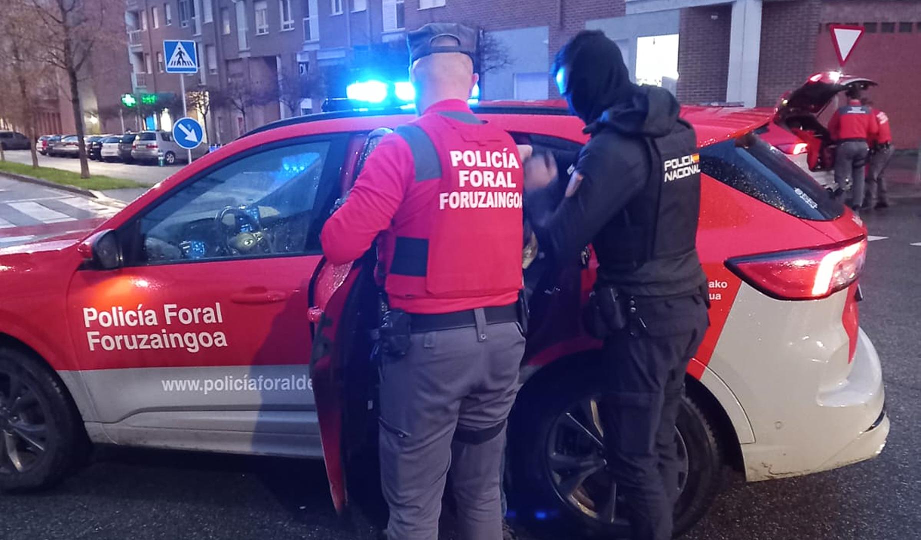 Un agente de la Policçia Foral y otro de la Policía Nacional introducen al agresor en un coche patrulla