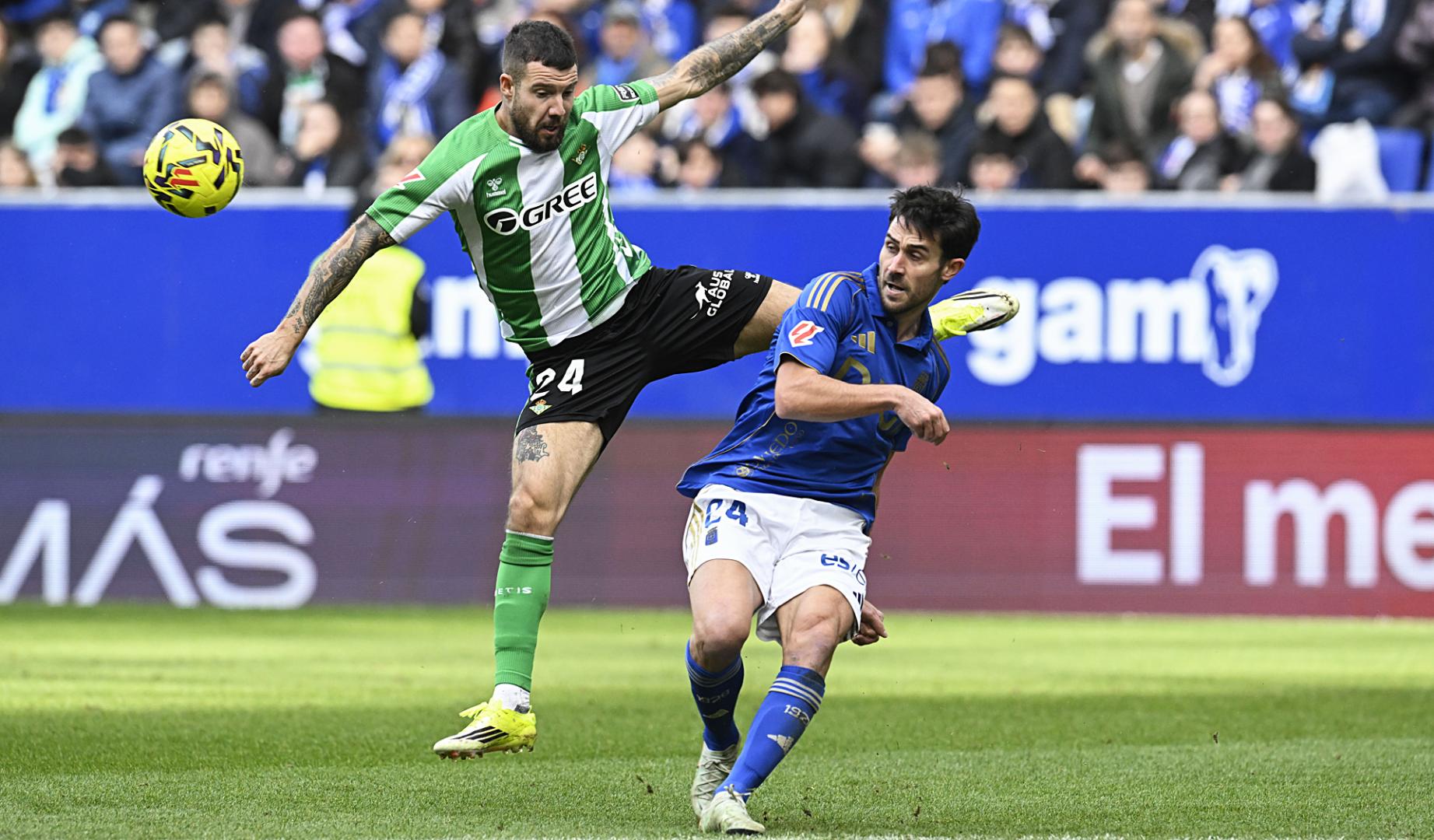 El defensa del Oviedo Lucas Ahijado despeja el balón ante la presión del bético Aitor Ruibal