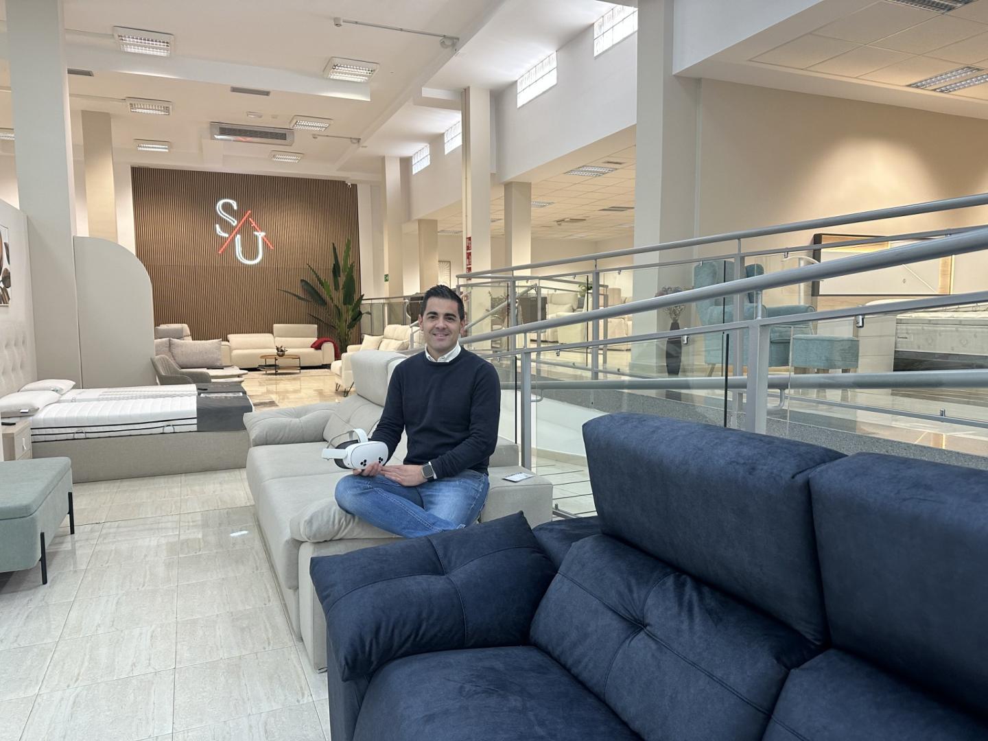 Sergio Urriza, en su tienda de muebles con las gafa de realidad virtual en la mano,