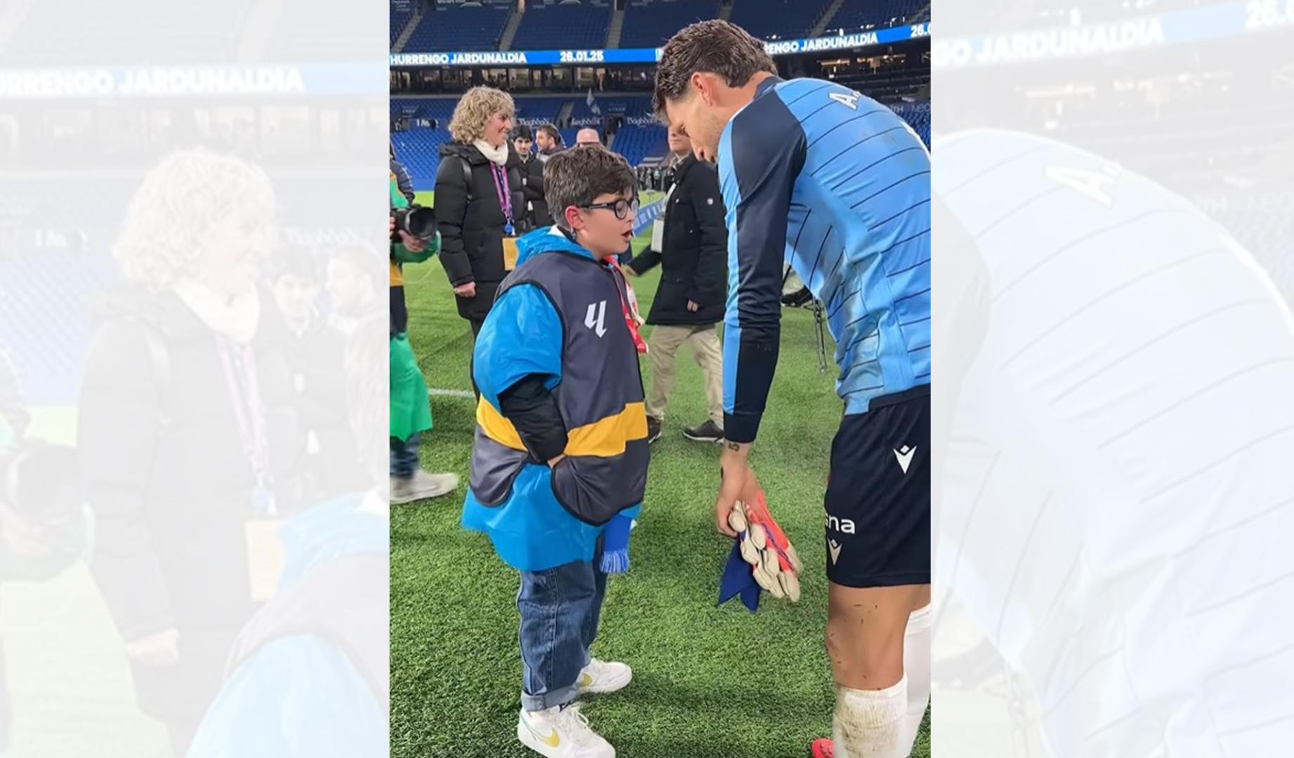 Momento en el que Álex Remiro regala sus guantes a Álvaro, un joven aficionado de la Real