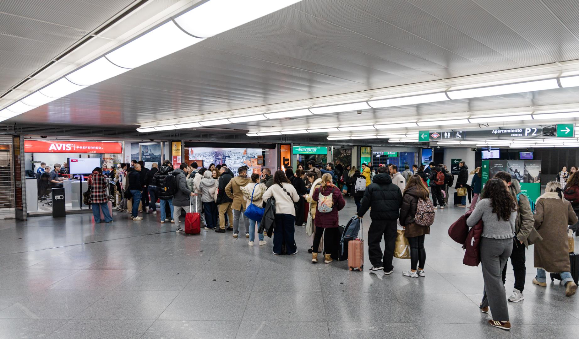 Decenas de personas haciendo cola en oficinas de alquiler de coches, en la estación Madrid-Puerta de Atocha-Almudena Grandes