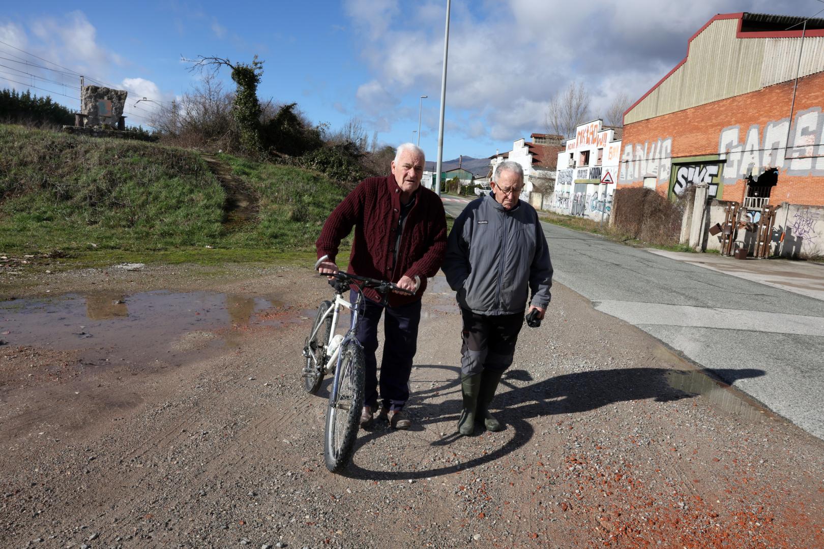 Manolo Gorriti Vicondo, de 89 años, junto a su amigo de infancia Josetxo Huarte Huarte, de 81, este martes en Uharte Arakil. Al fondo, a la izquierda, el monolito de piedra que recuerda a las víctimas del accidente.