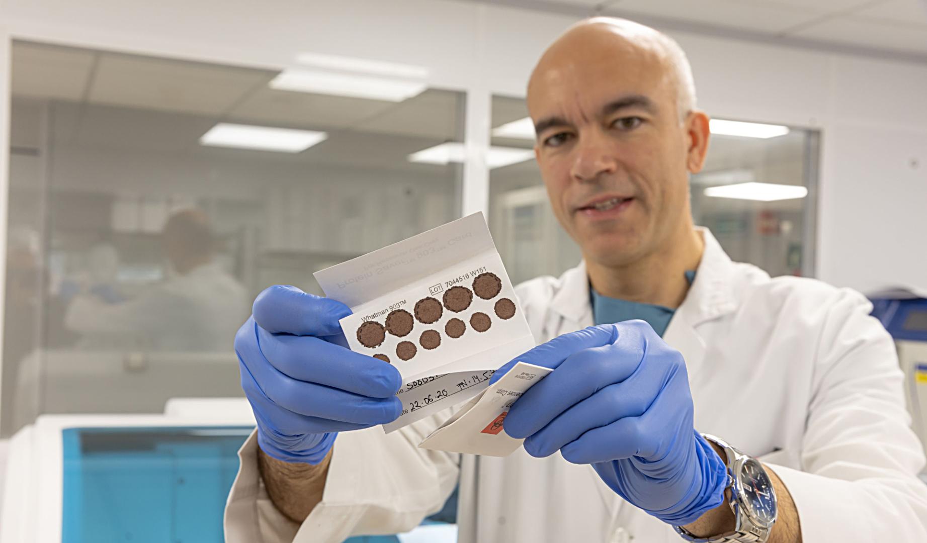 El doctor Gabriel Reina sujeta una tarjeta con una muestra de sangre seca.