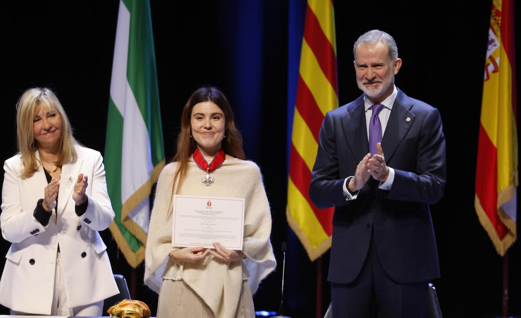 El rey Felipe VI y la presidenta del Consejo General del Poder Judicial (CGPJ), Isabel Perelló, aplauden a la número uno de la promoción, Ángela Sanz Sanz, durante el acto de entrega de despachos a los 121 jueces de la nueva promoción