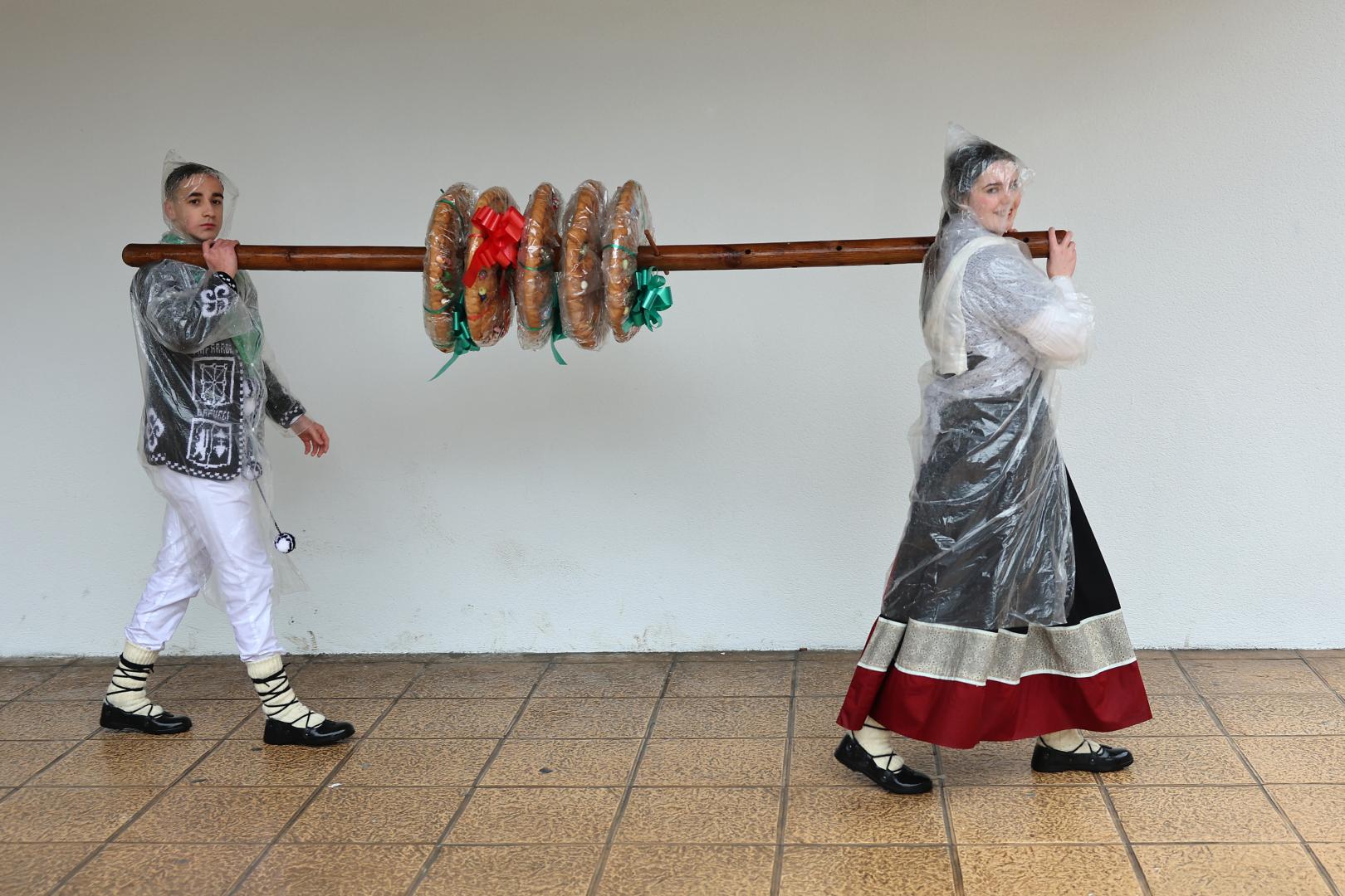 Unai De los Santos Rodríguez y Ane Arregui Larraza portan el palo con las tortas ensartadas.
