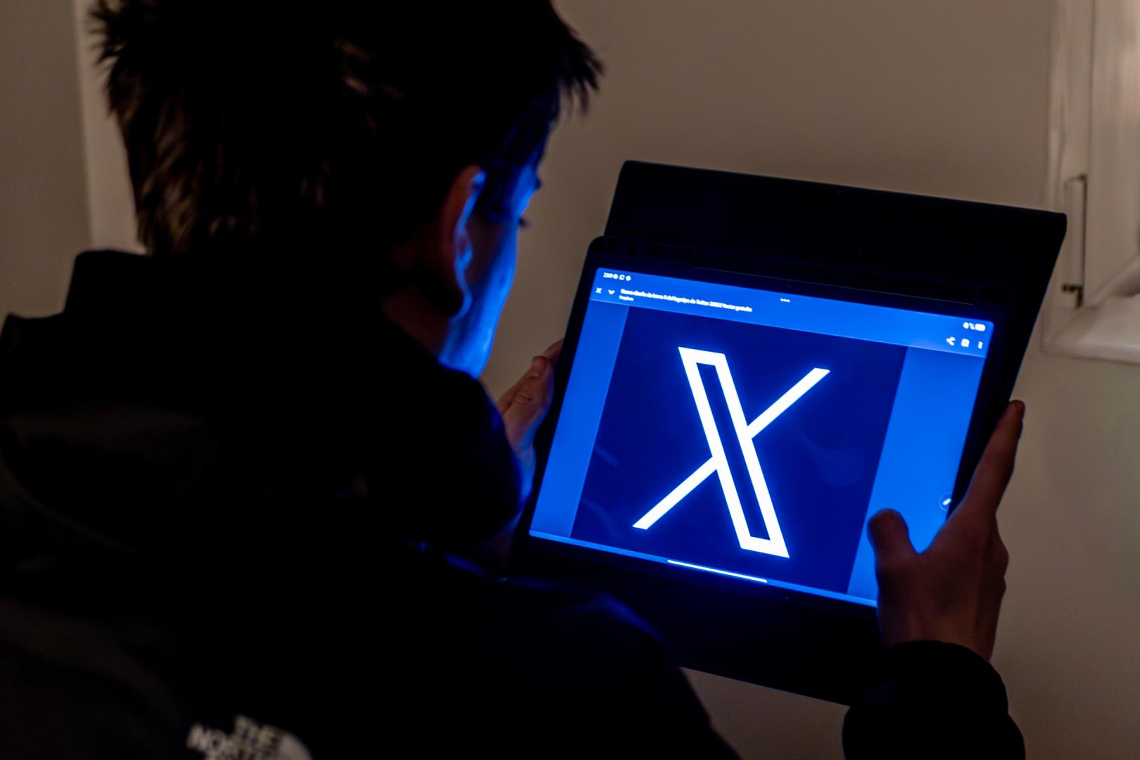Un joven usa una tablet en la que se ve el logo de la red social X, antes Twitter