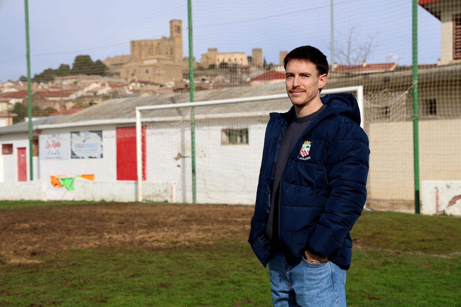 El capitán del Artajonés, David Echeverría, posa en el campo de fútbol con el cerco al fondo.