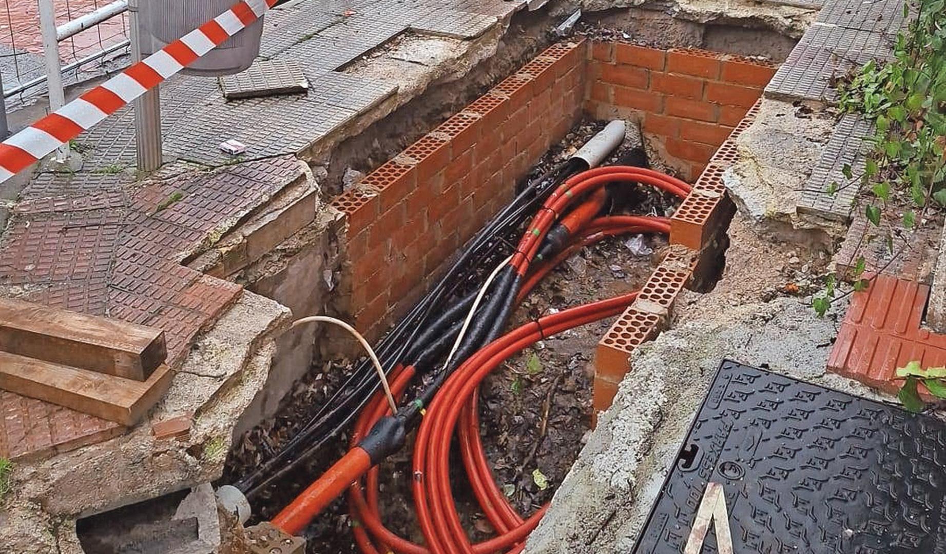 Vista del cableado visible en la zanja abierta en la calle del bloque de viviendas. Al fondo, la avenida Eulza