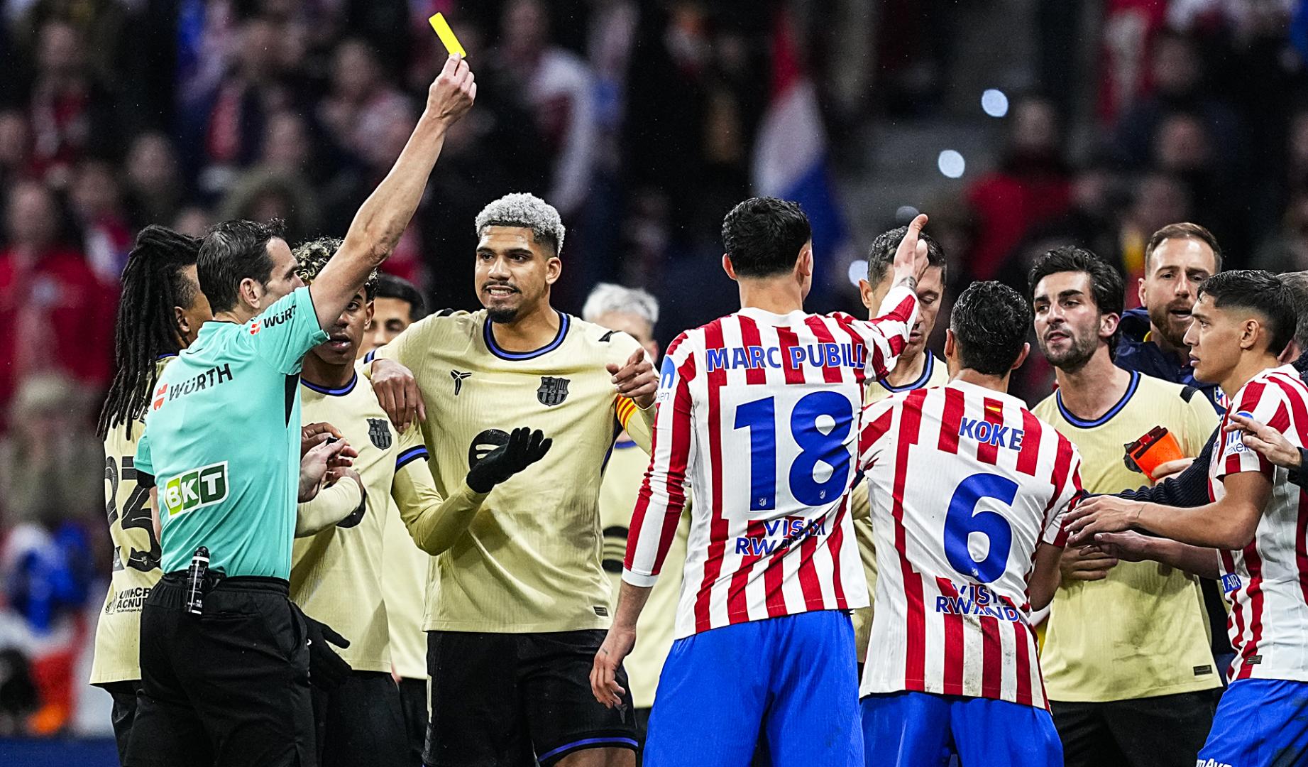 El colegiado muestra una cartulina amarilla durante la ida de la semifinal de la Copa del Rey entre F.C. Barcelona y Atlético de Madrid