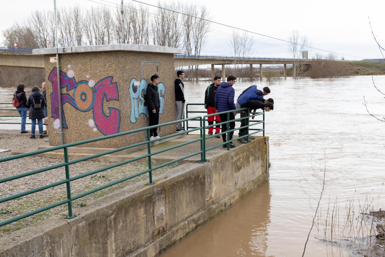 Varias personas observan la crecida del río Ebro en Castejón
