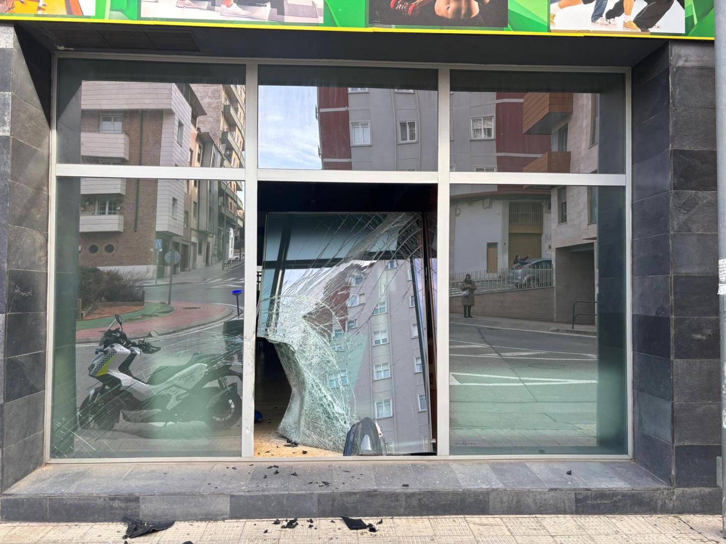 Imagen del escaparate roto de un establecimiento contra el que chocó una motocicleta, cuyo conductor se dio a la fuga