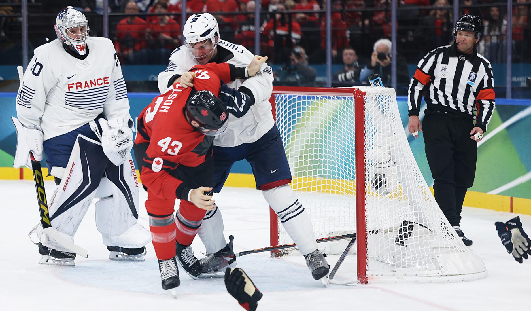El canadiense Tom Wilson (de rojo) enzarzado con el galo Pierre Crinon (de blanco) durante el Canadá-Francia de los Juegos Olímpicos de Milán Cortina