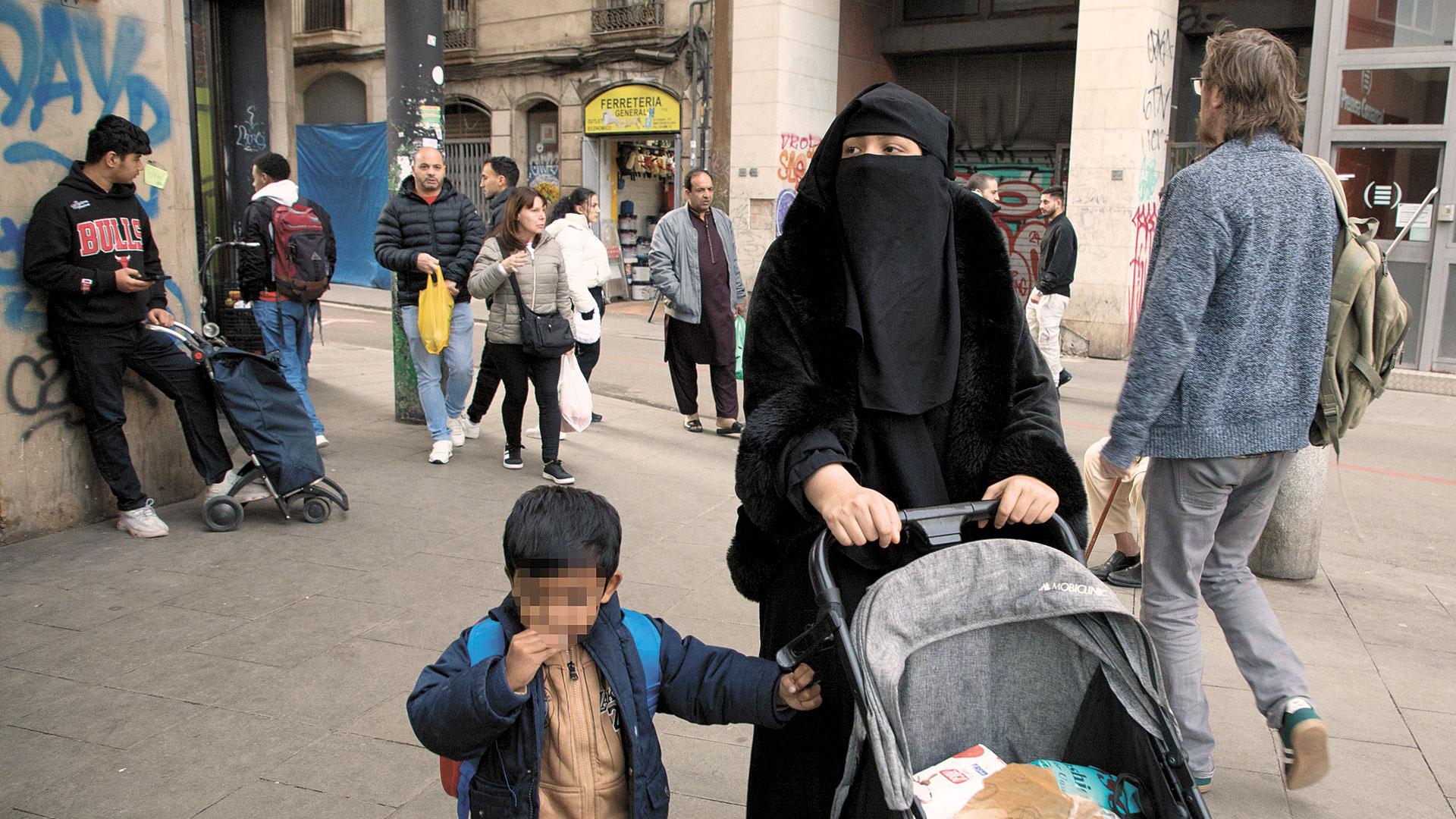 Una mujer con burka camina por una calle del barrio de El Raval de Barcelona