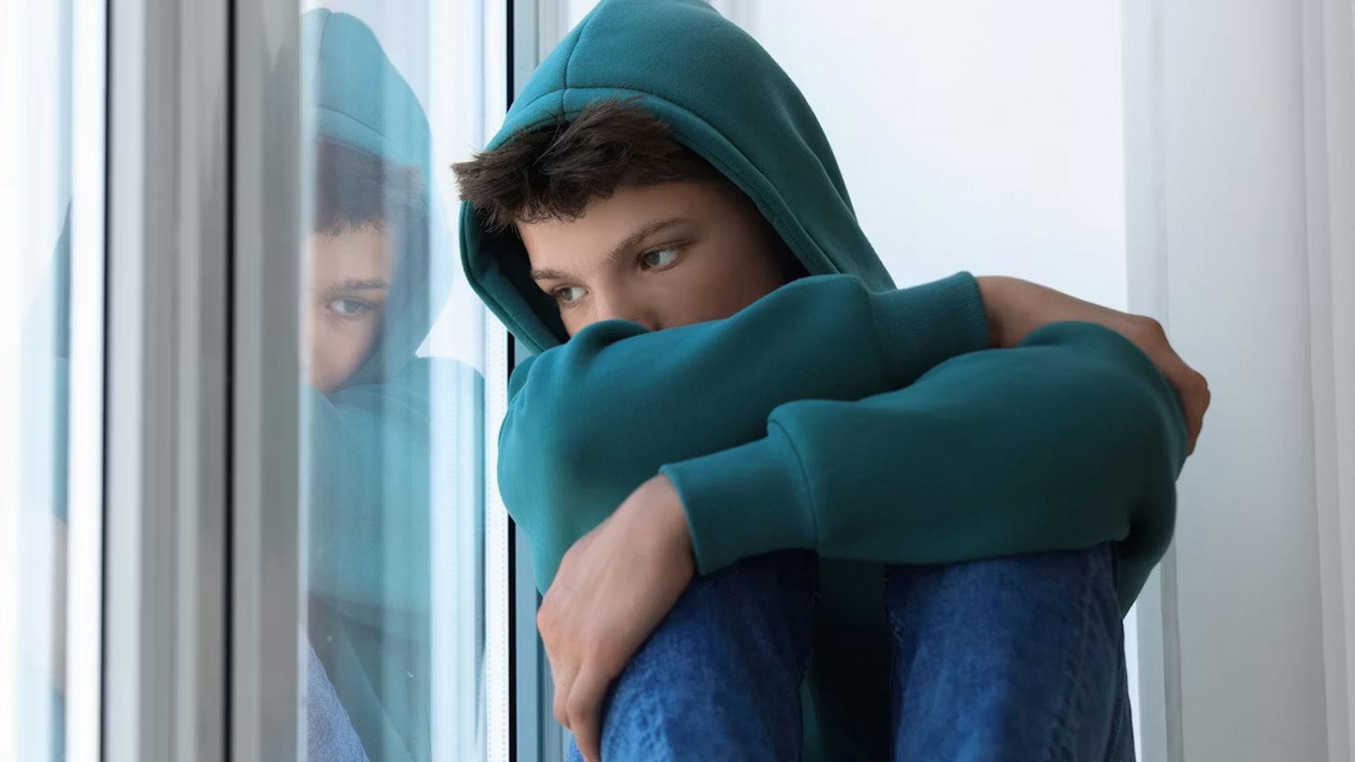 Un adolescente pensativo mirando por la ventana