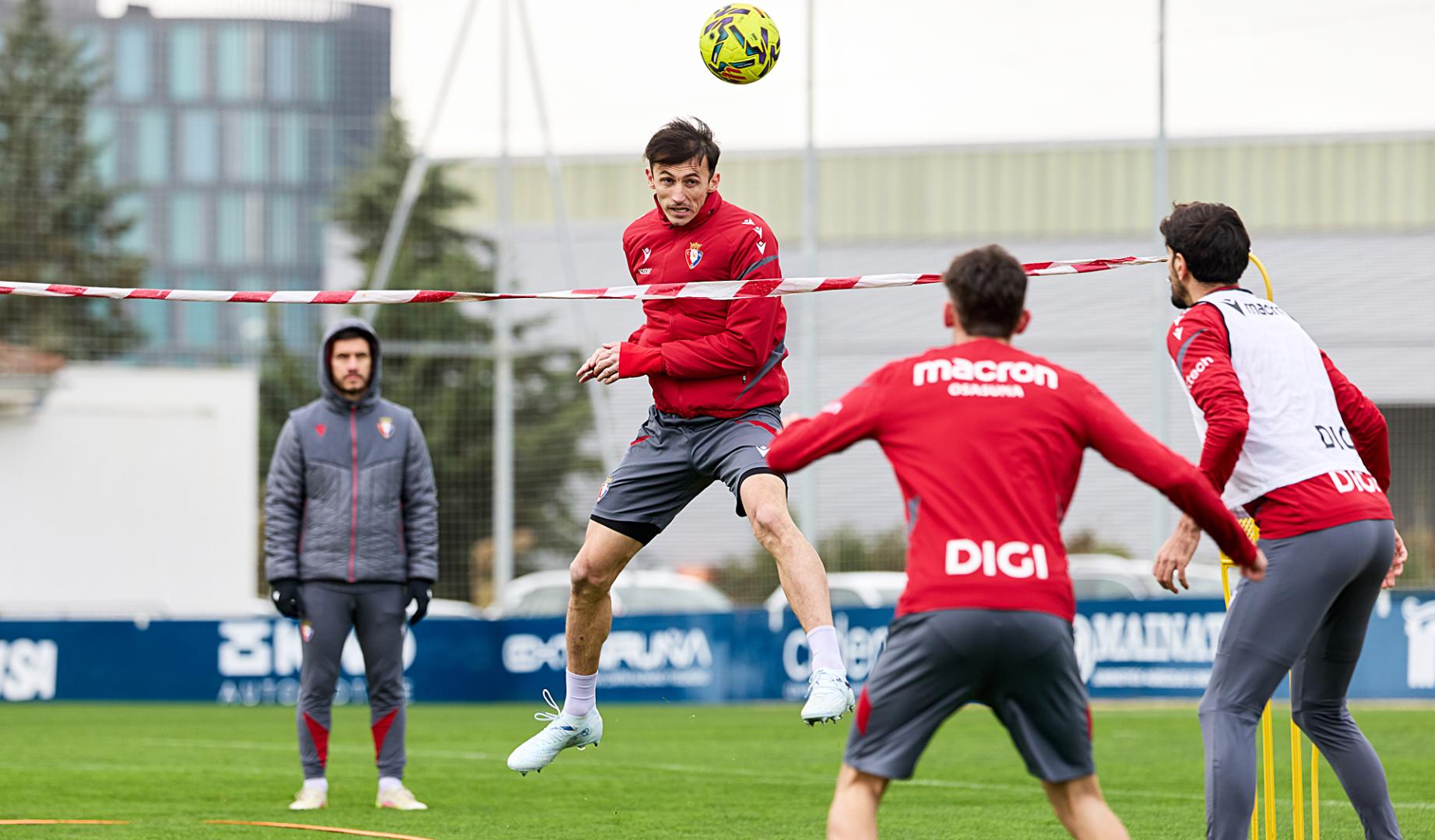 Ante Budimir cabecea el esférico durante el fútbol-tenis donde Aimar Oroz y Alejandro Catena esperan al otro lado de la red, este jueves 19 de febrero en Tajonar