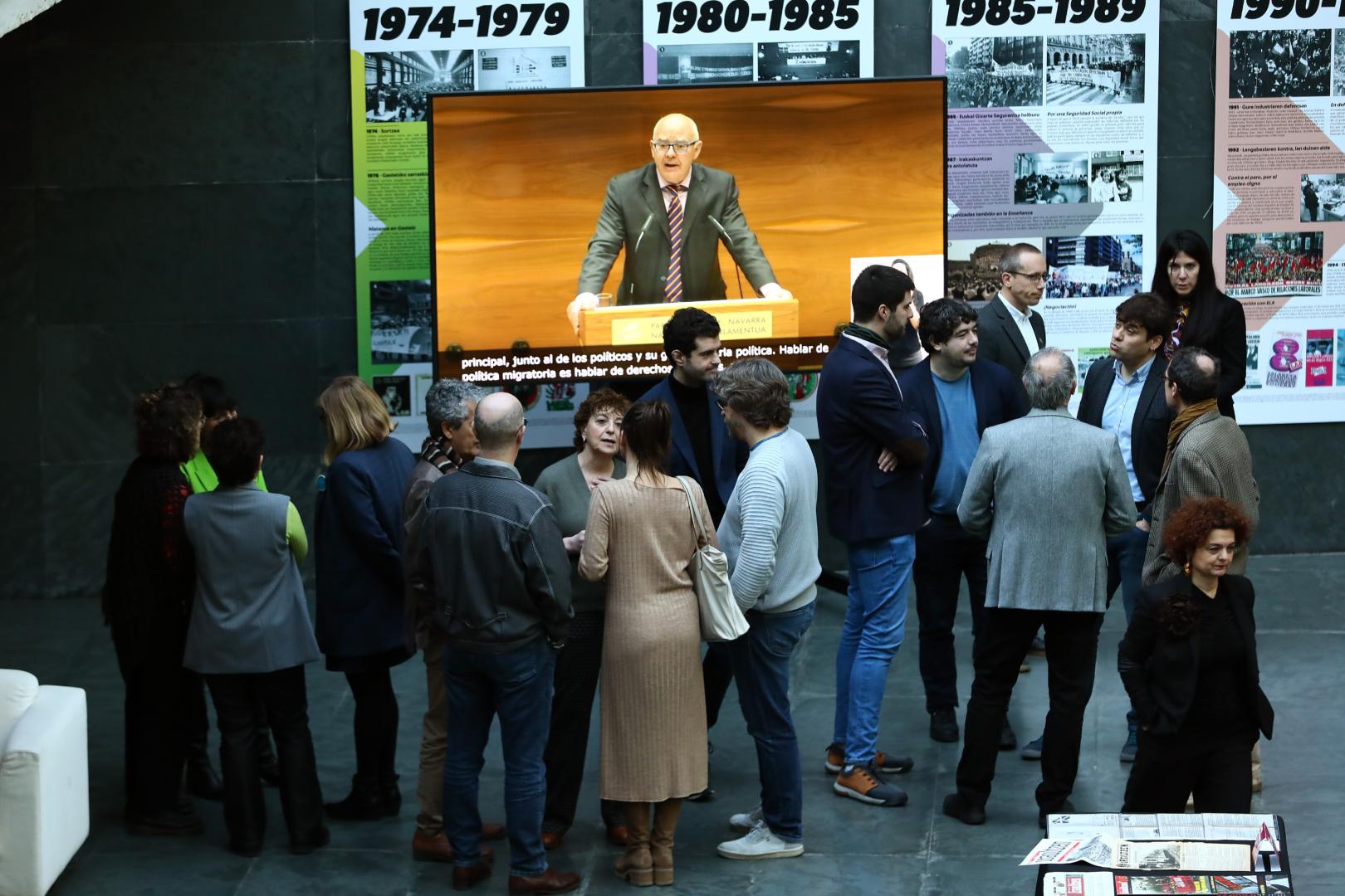 Parlamentarios de otros grupos, en el atrio de la Cámara mientras la pantalla proyecta la intervención en el salón de plenos del portavoz de Vox, Emilio Jiménez