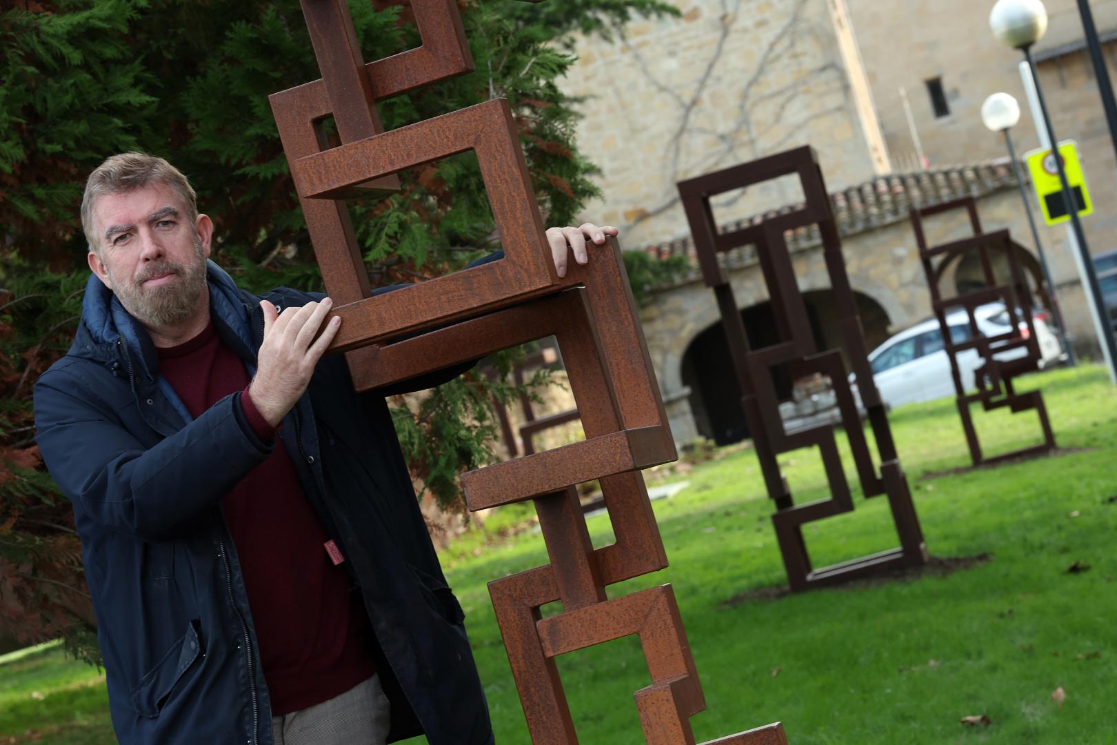 Ariel Elizondo posa con una de las esculturas de su muestra 'Densités' (Densidades') colocadas en la ruta del Camino de Santiago a su paso por el campus de la Universidad de Navarra.