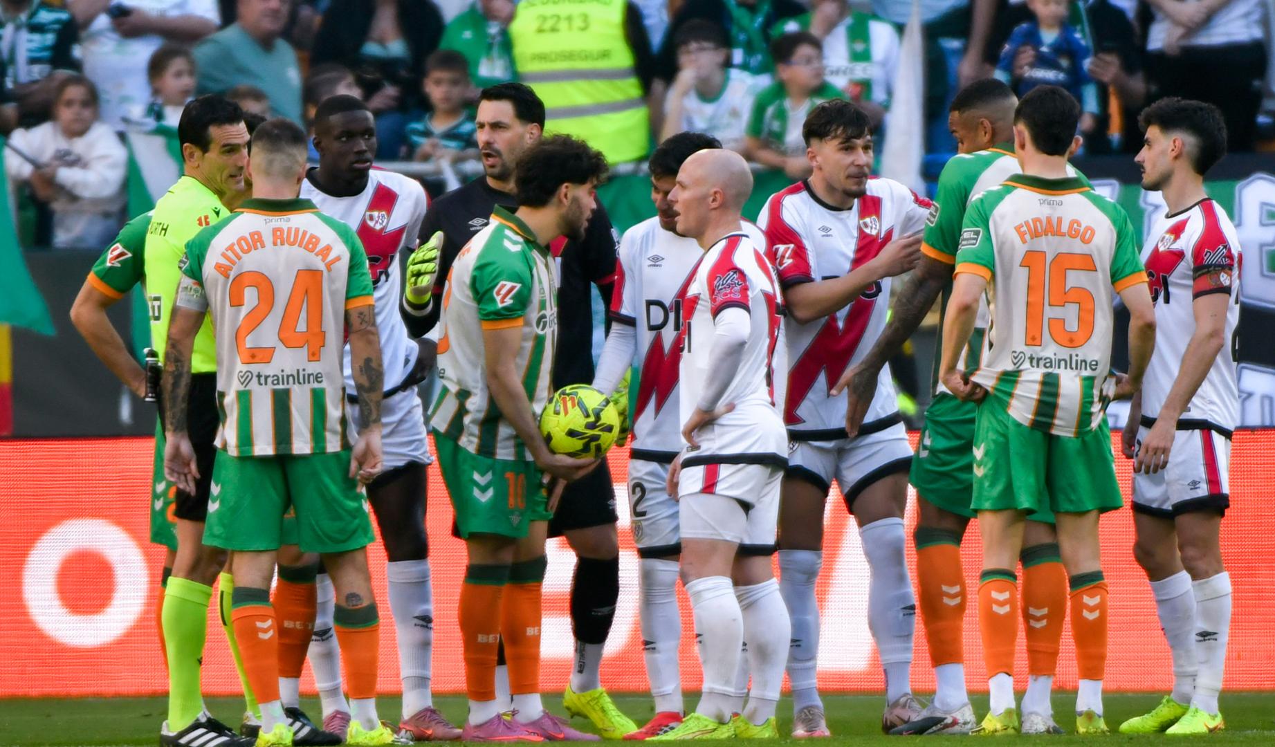 El delantero del Betis Ez Abde (c-i) conversa con el centrocampista del Rayo Vallecano Isi Palazón (c-d)