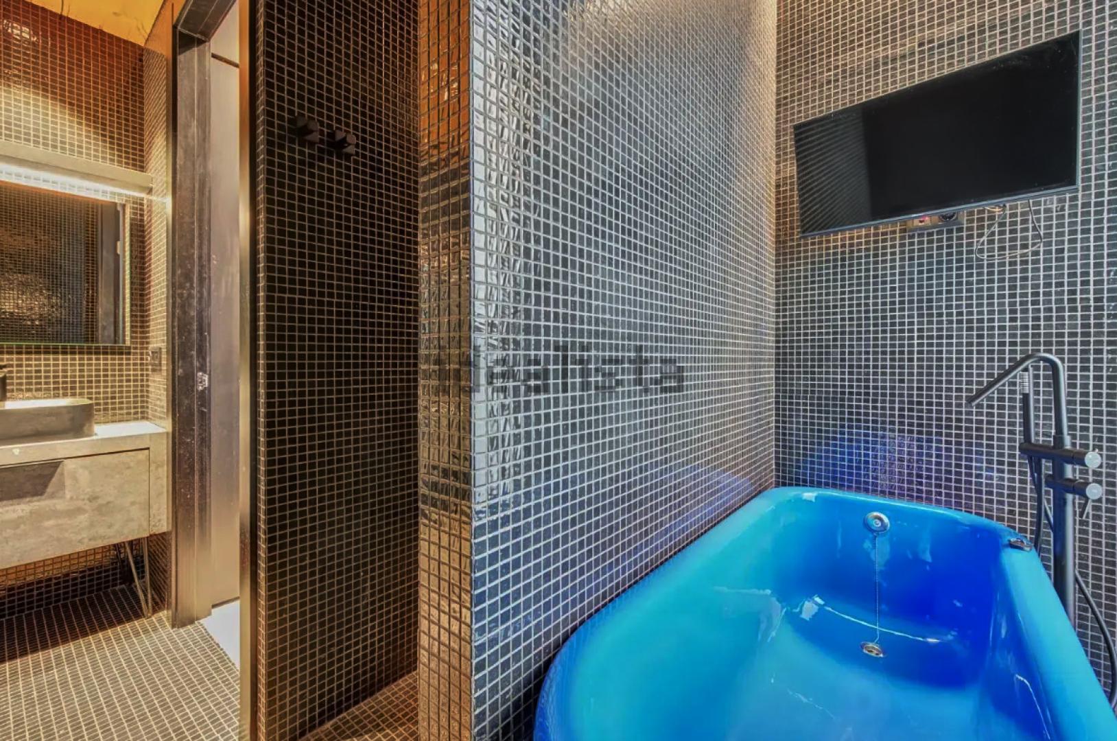 Bañera azul con televisión en el dormitorio principal