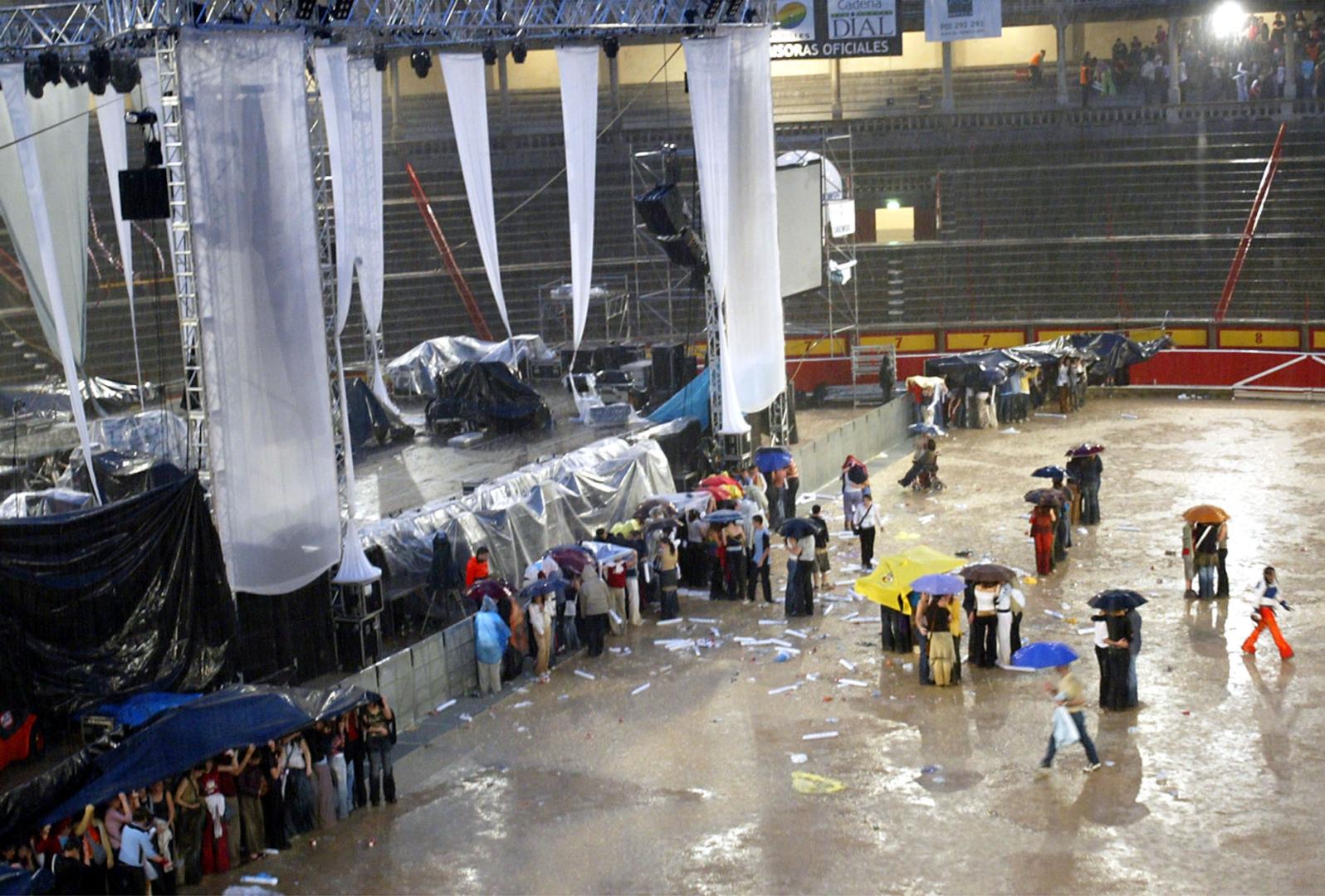 Las personas que permanecieron junto al escenario se protegieron con paraguas y lonas