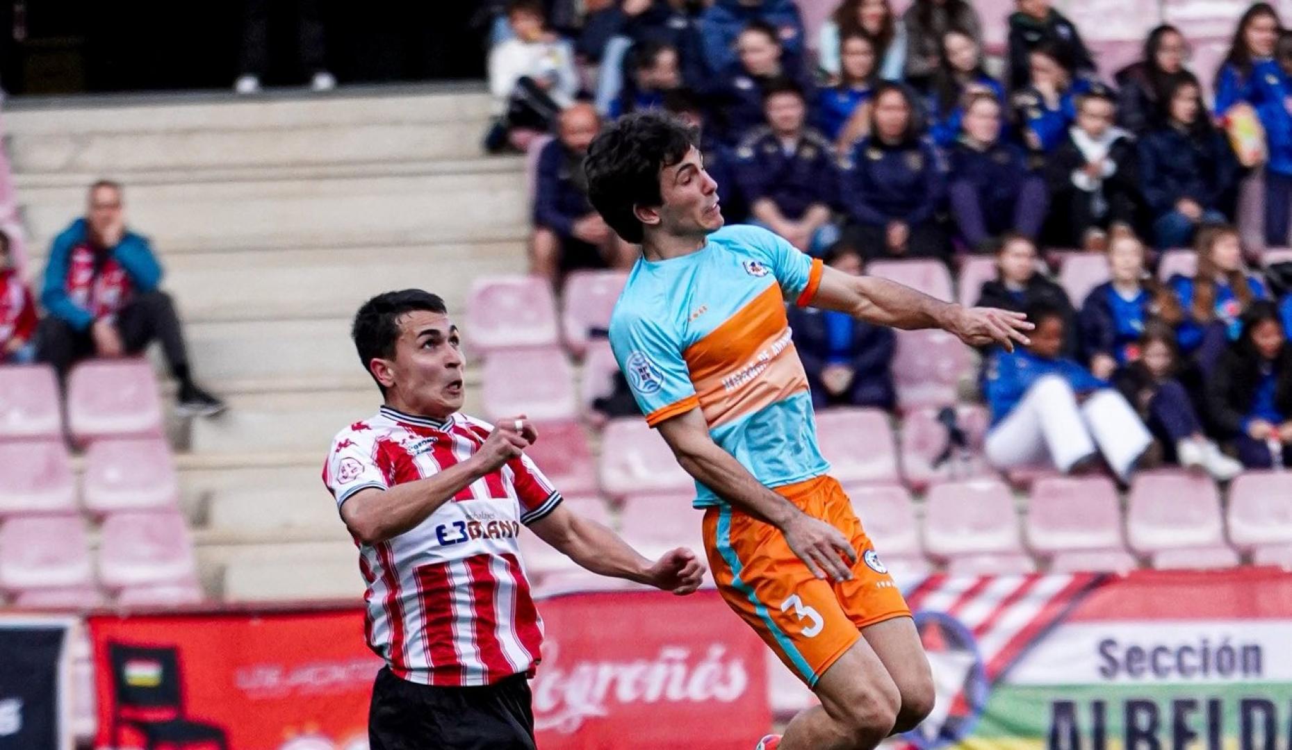 Eloi Goñi, futbolista de la Mutilvera, salta ante Arman Lazkano, de la SD Logroñés