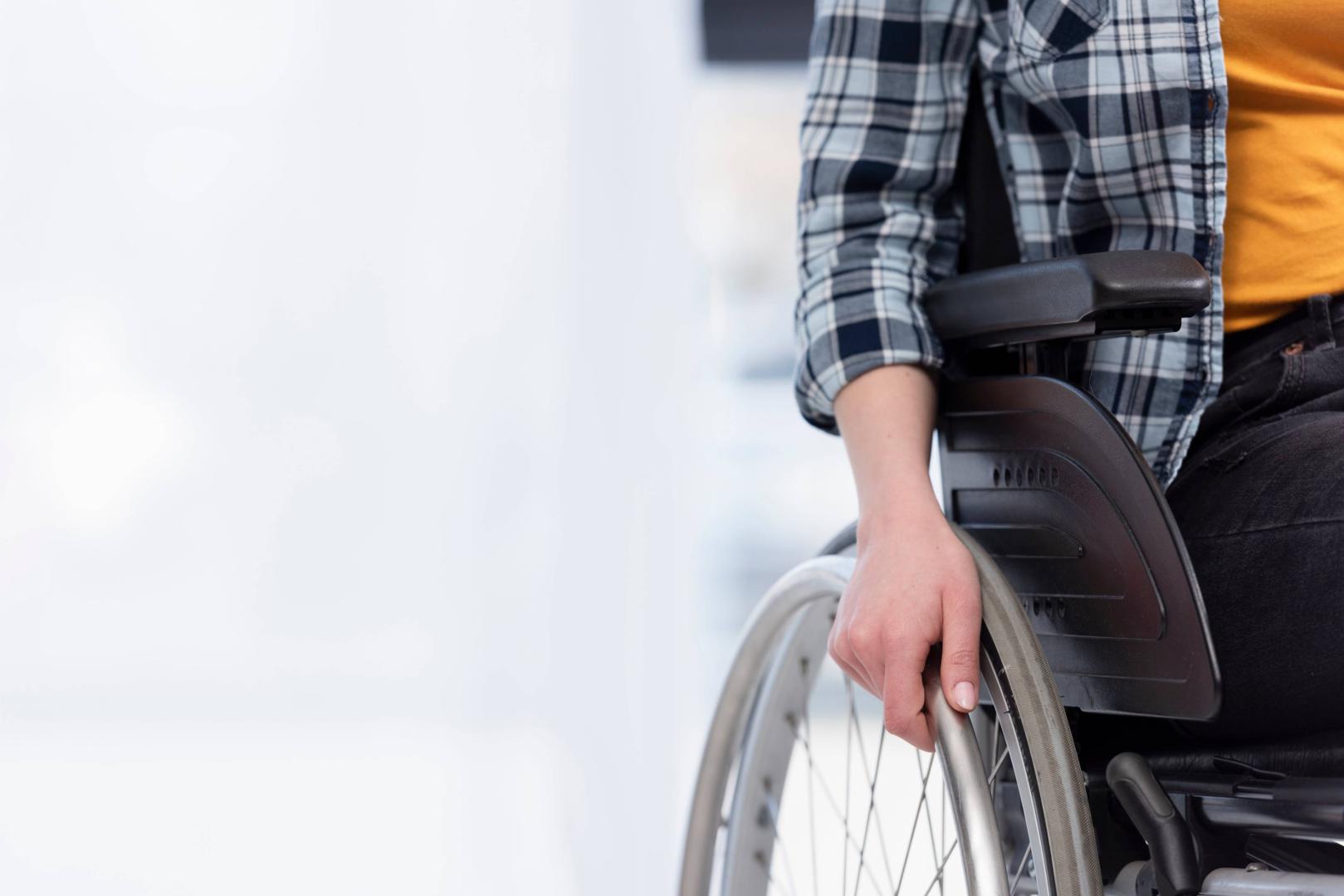 Una persona con discapacidad se apoya en su silla de ruedas