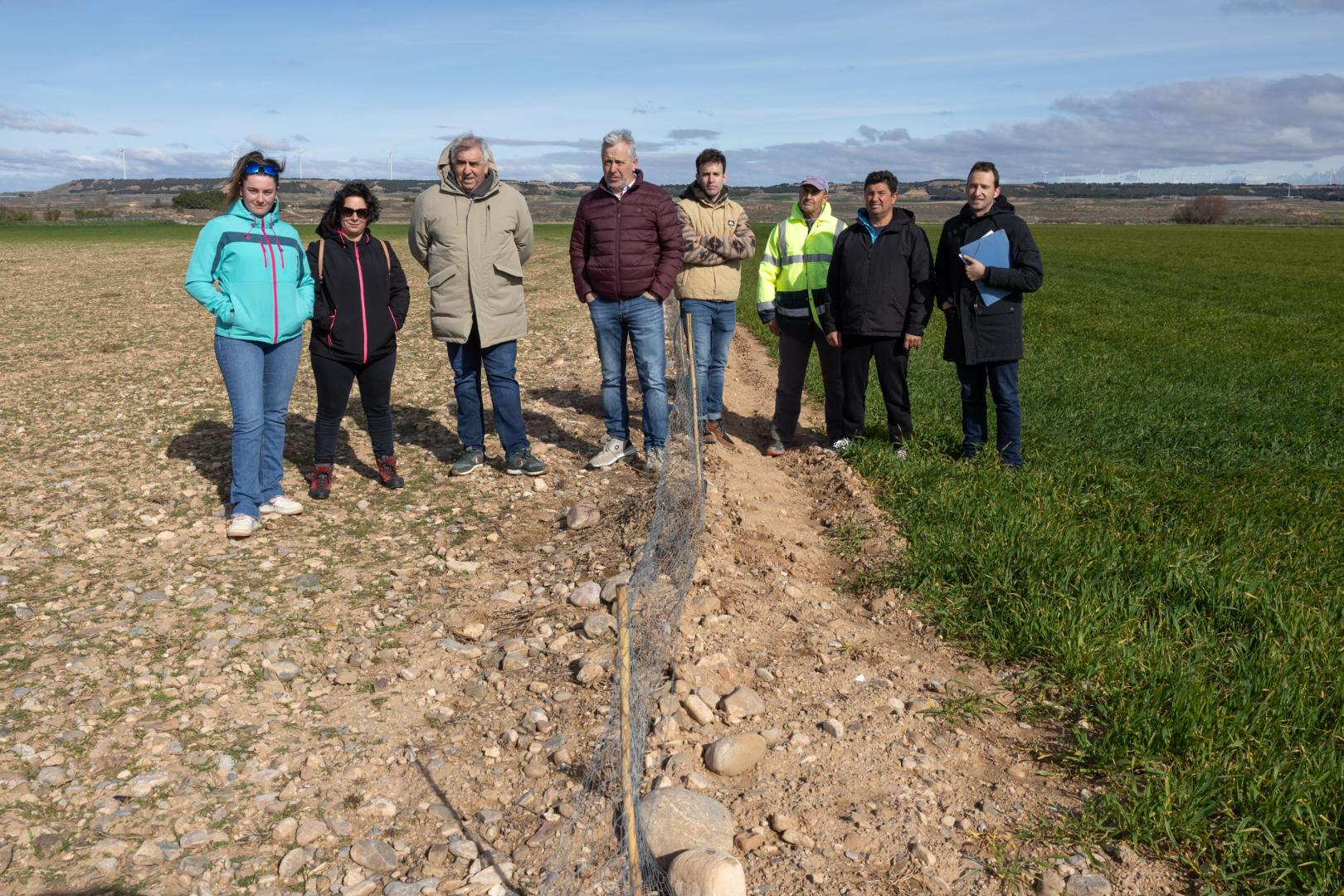 En la foto, tomada este lunes en Cascante, se aprecia la diferencia entre un campo de cereal arrasado por los conejos -a la izda.- junto a otro protegido por una valla -a la dcha.-. De izda. a dcha.: las agricultoras Patricia Martínez Pes y Jenifer Redondo Martínez; Luis Miguel Serrano Cornago y Félix Bariáin Zaratiegui (UAGN); los agricultores Alberto Alfaro Calvo, Javier Díaz Arnedo, y Jesús Sola Hernández; y David Navarro Lorente (UAGN).  b
