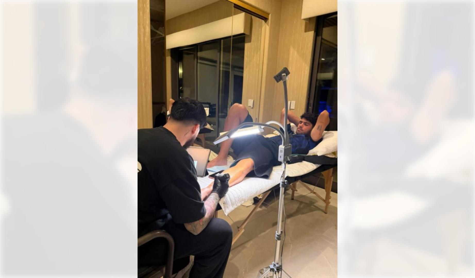 Foto difundida en la cuenta de Instagram de Carlos Alcaraz del momento en que le realizan un tatuaje en California durante la disputa del Masters 1.000 de Indian Wells y que recuerda su reciente éxito en el Abierto de Australia