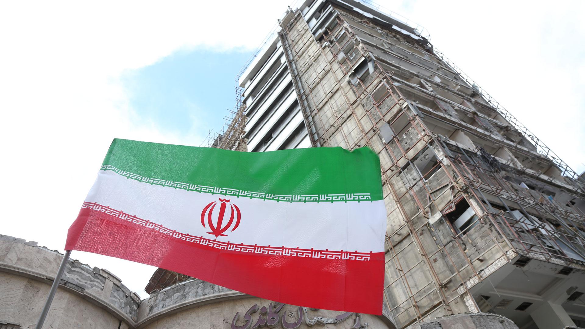 Una bandera nacional iraní ondeando por un manifestante frente a un hospital dañado en un ataque estadounidense-israelí, en Teherán