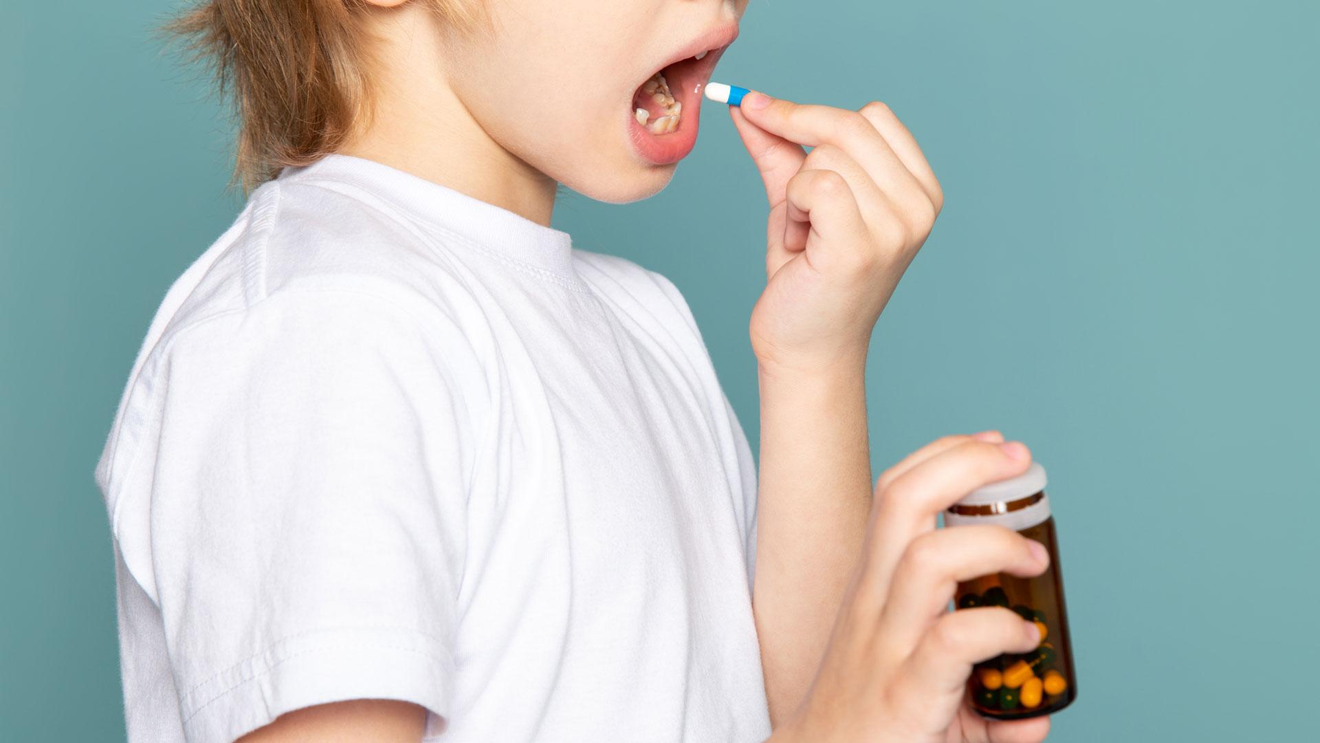 Un niño se toma una pastilla de antibiótico