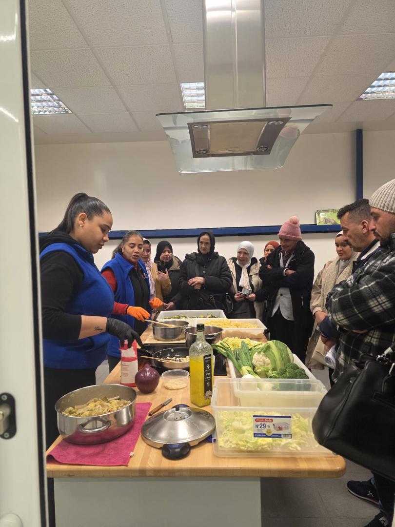 Ely y su compañera cocinan verdura de Navarra para las personas migrantes.