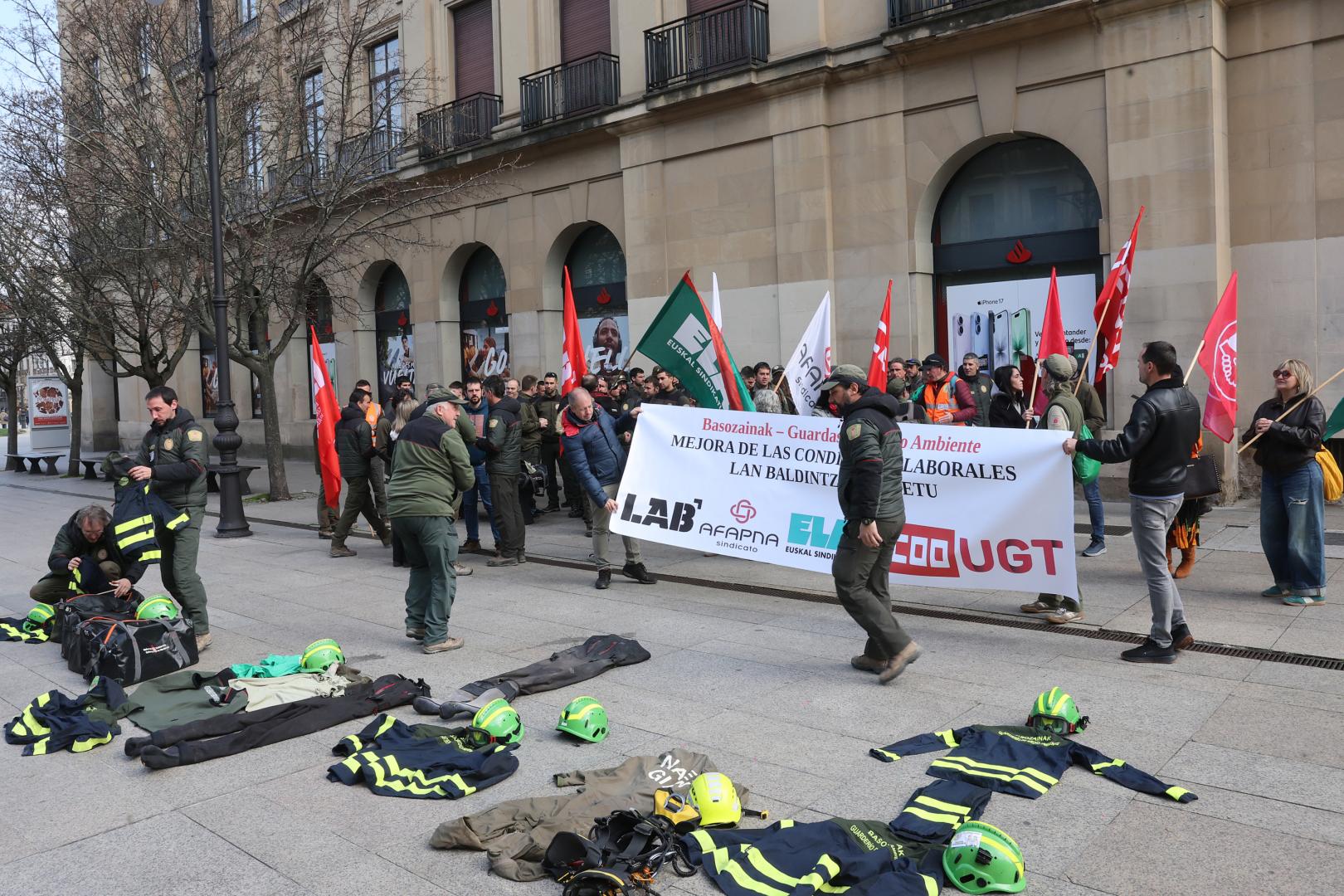Los participantes en la concentración, con prendas de trabajo en el suelo y delante del Palacio de Navarra