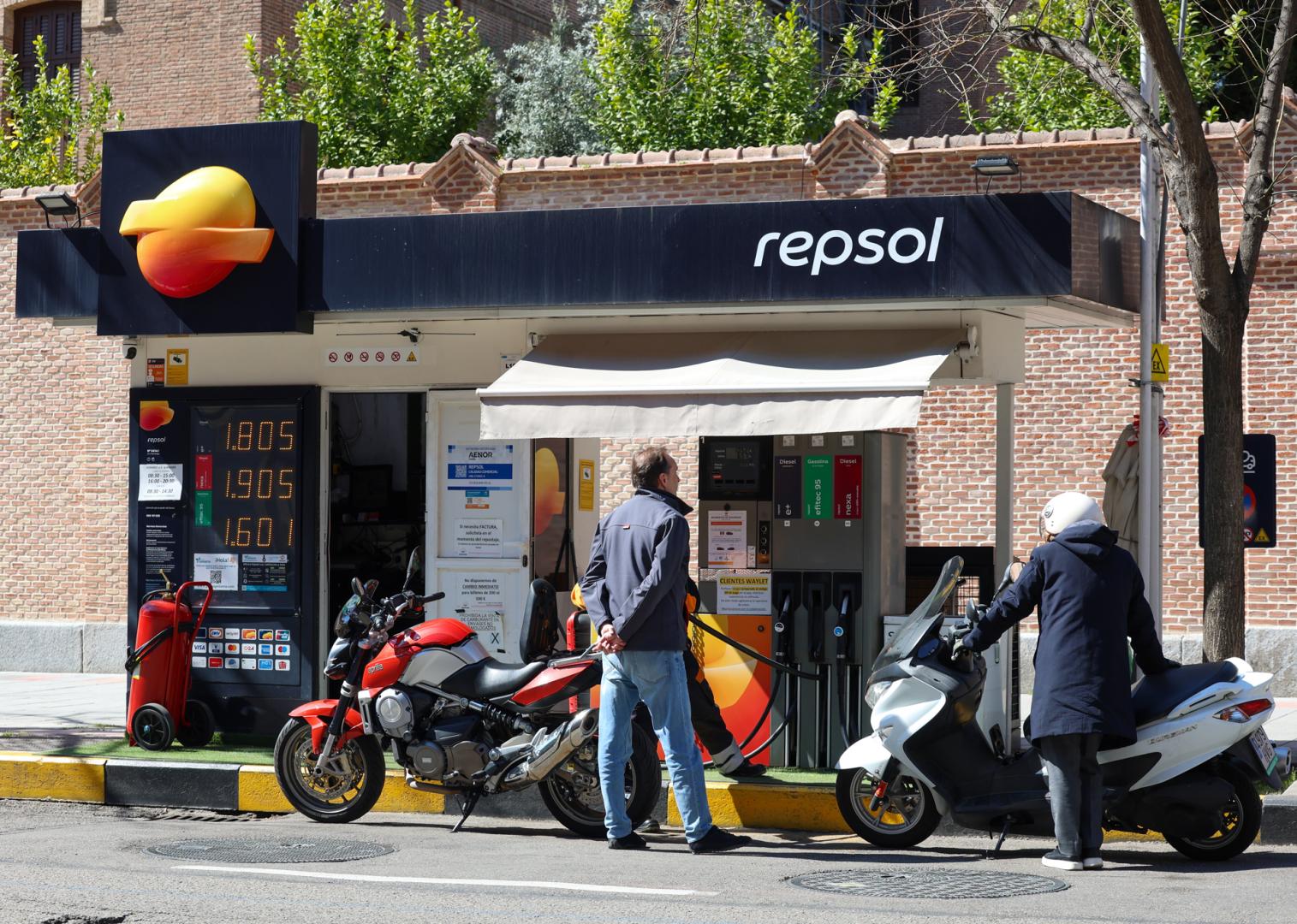 Dos personas repostan sus motocicletas este lunes en una gasolinera de Madrid