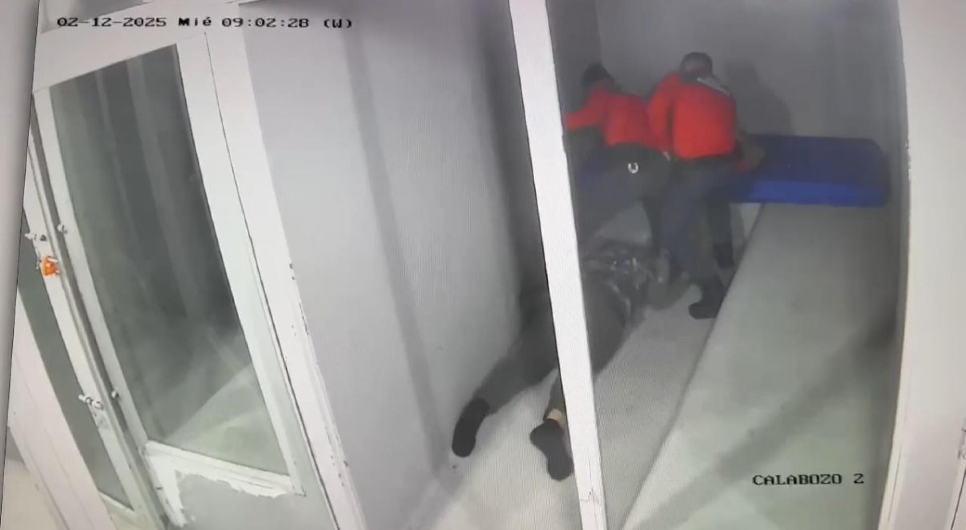 Un fotograma de la grabación de calabozos: dos de los agentes acusados (a la izquierda el que propinó los golpes), tras tirar al detenido al suelo para engrilletarlo