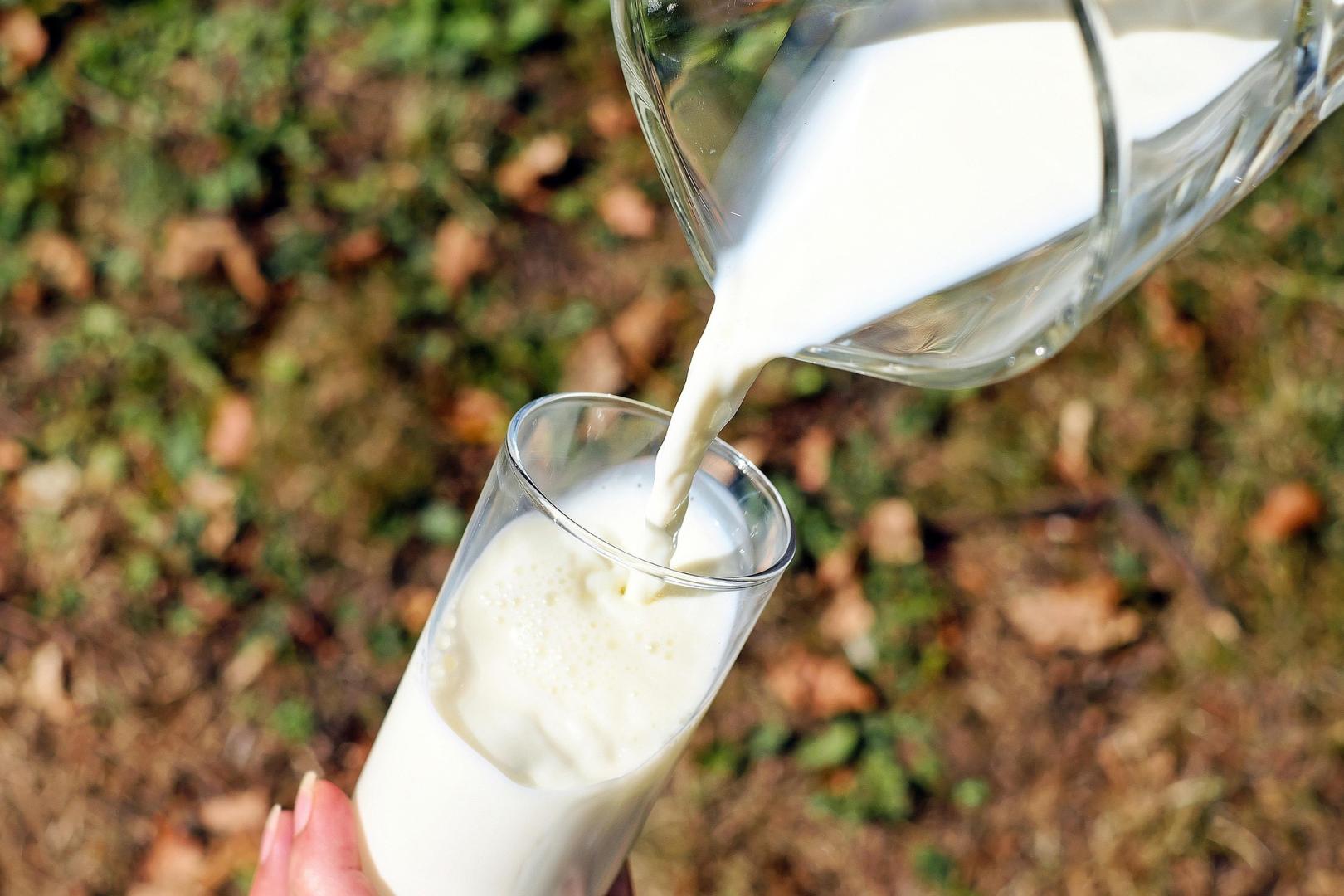 Imagen de archivo de una persona sirviendo un vaso de leche