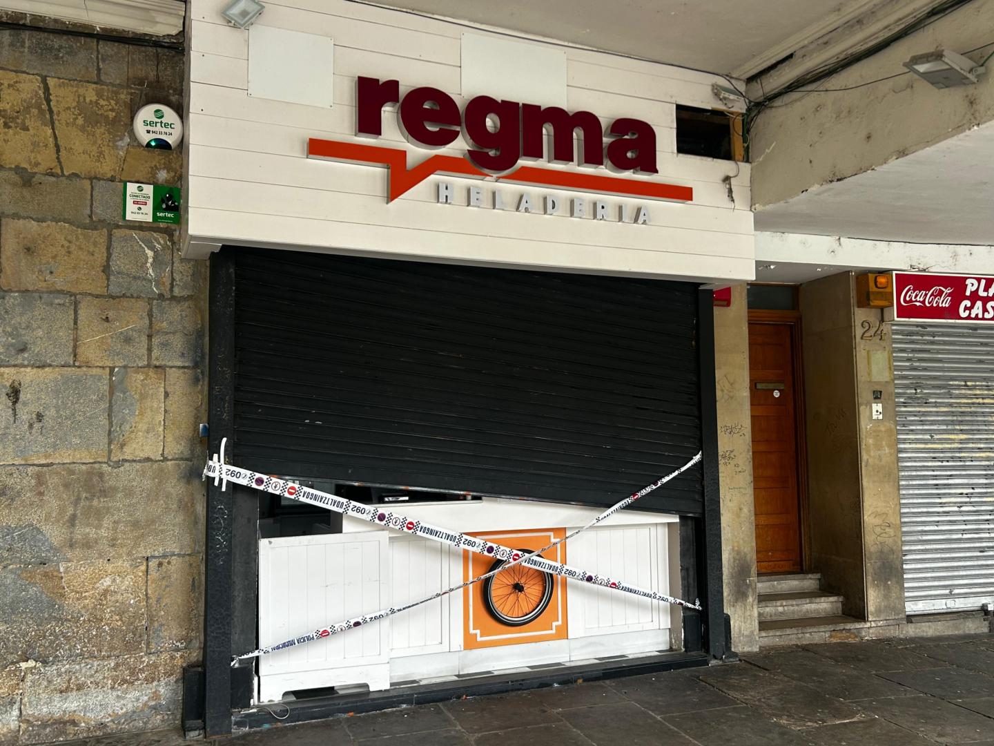 Precinto policial en el local, con los daños en la persiana