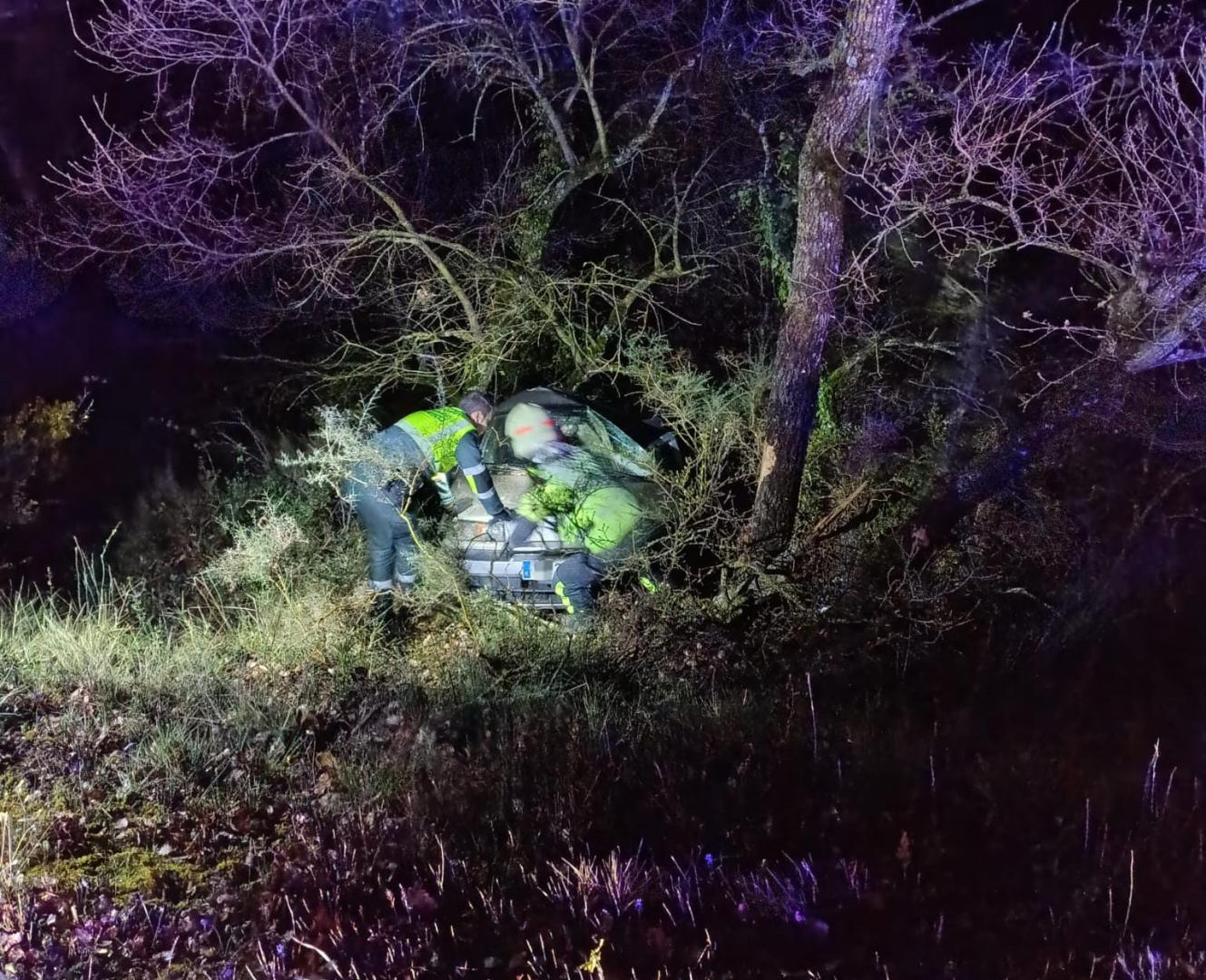 Agentes de la Guardia Civil, junto al vehículo siniestrado, que cayó por un talud