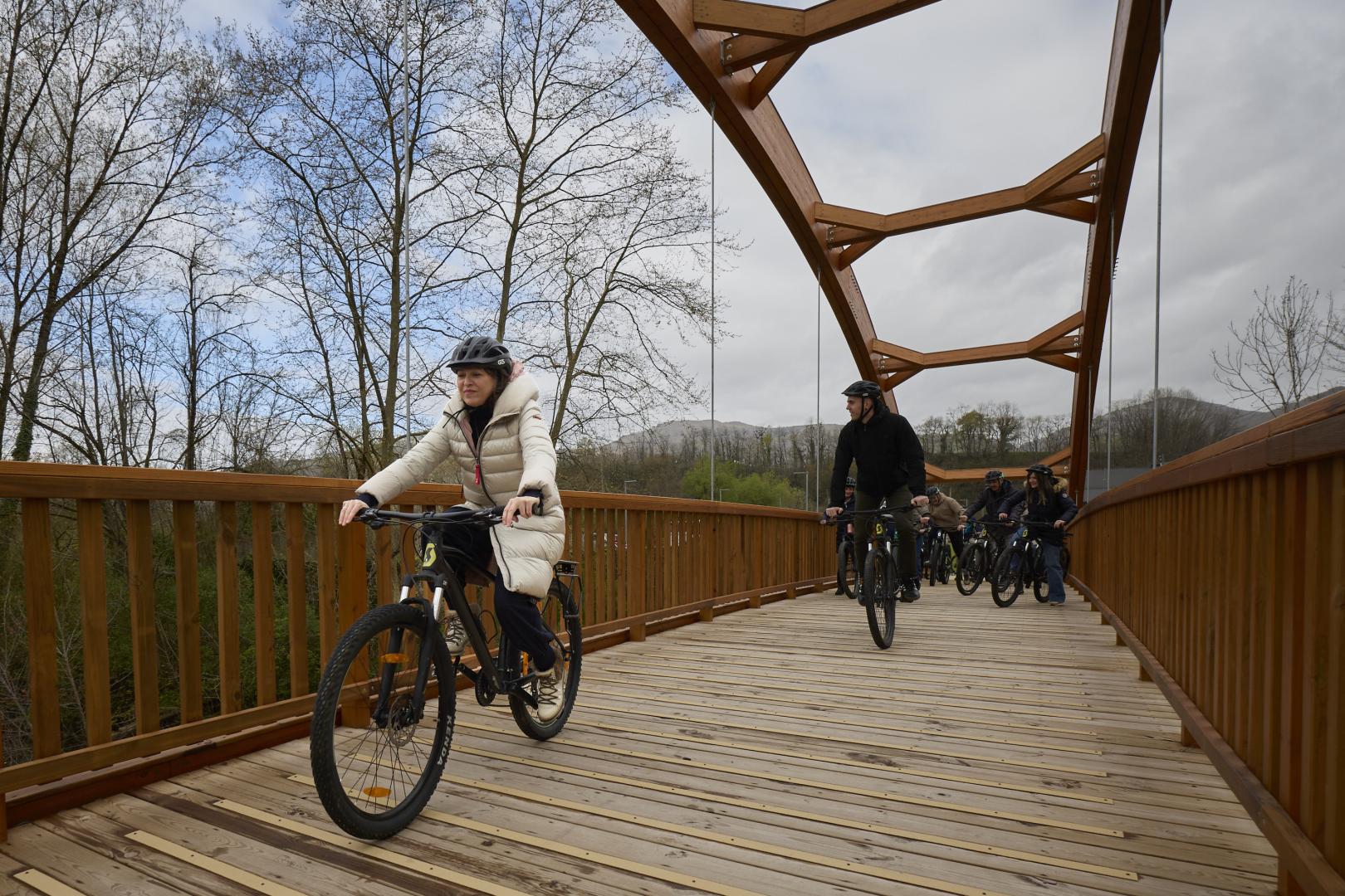 Un grupo de asistentes a la visita oficial de este martes atraviesa en bici la pasarela de Lekaroz.