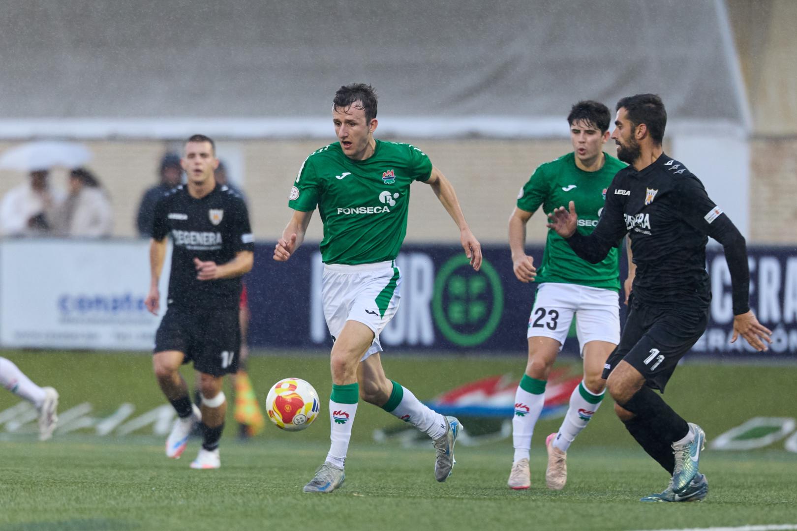 Unai Martínez 'Budi', del San Juan, conduce el balón ante Mikel Santamaría, defensa del Izarra