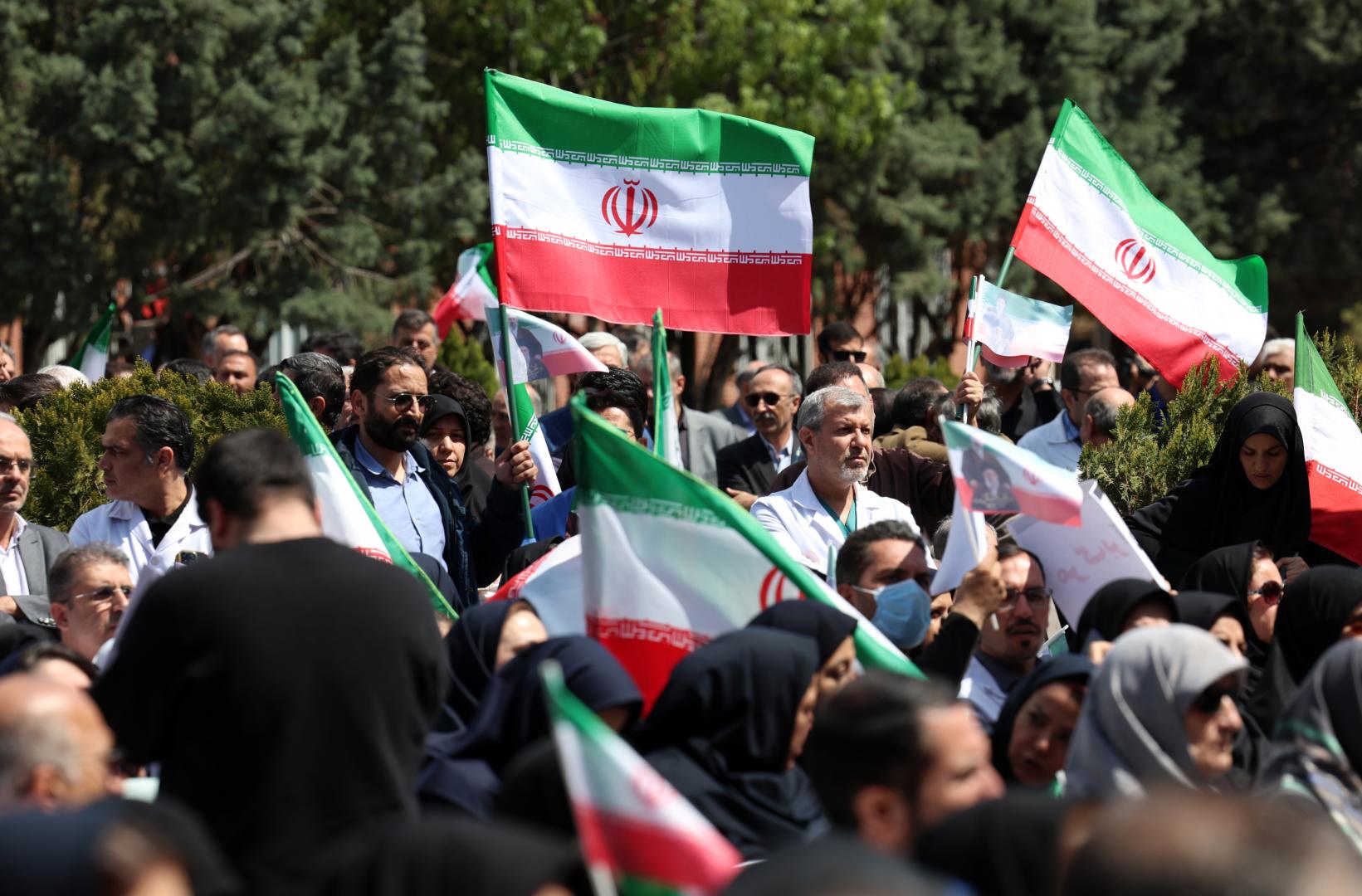Miembros del personal sanitario iraní, portando banderas iraníes, participan en una protesta contra los ataques estadounidenses e israelíes contra instalaciones sanitarias en el Hospital Imam Khomeini de Teherán, Irán