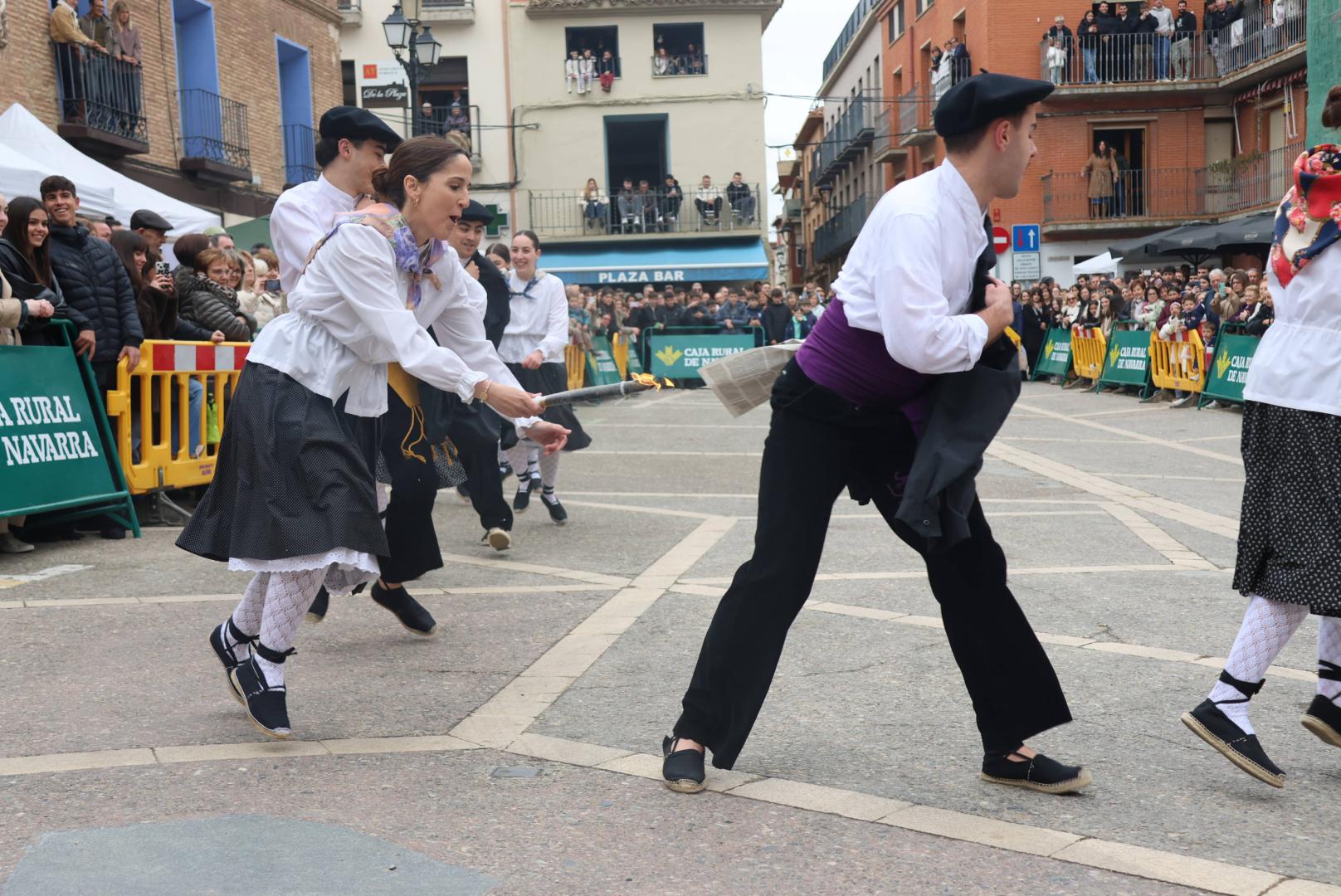 Una danzari de Mendianike intenta quemar el plego al compañero que lleva delante