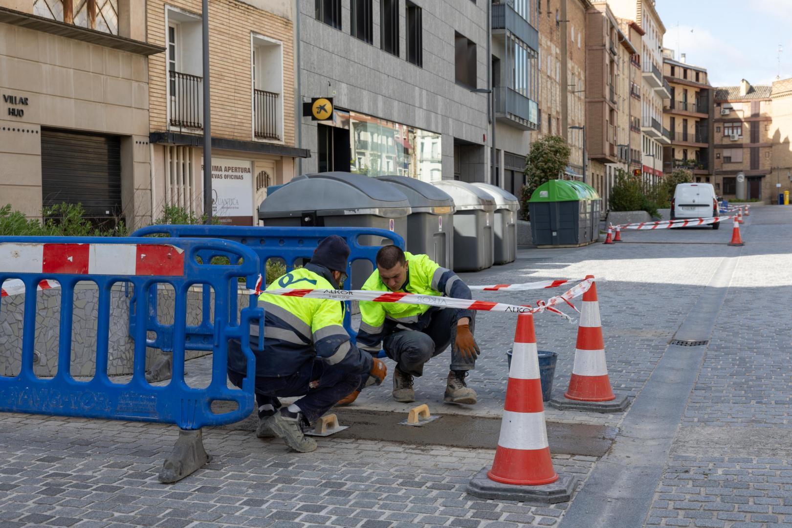 Dos operarios reparan los daños aparecidos en el pavimento de la calle Muro de Tudela