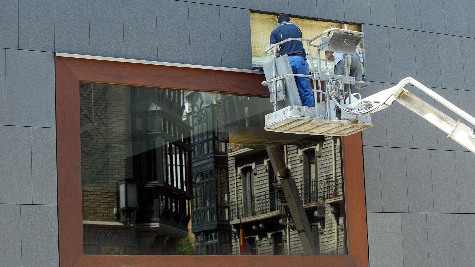 Operarios arreglando un grupo de placas de granito que recubren la fachada del edificio de Baluarte