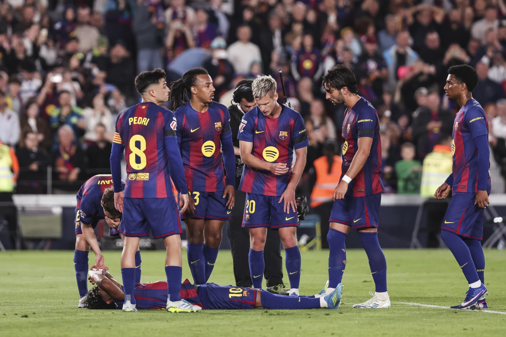 Los jugadores del Barcelona rodean a Lamine Yamal, tendido en el suelo