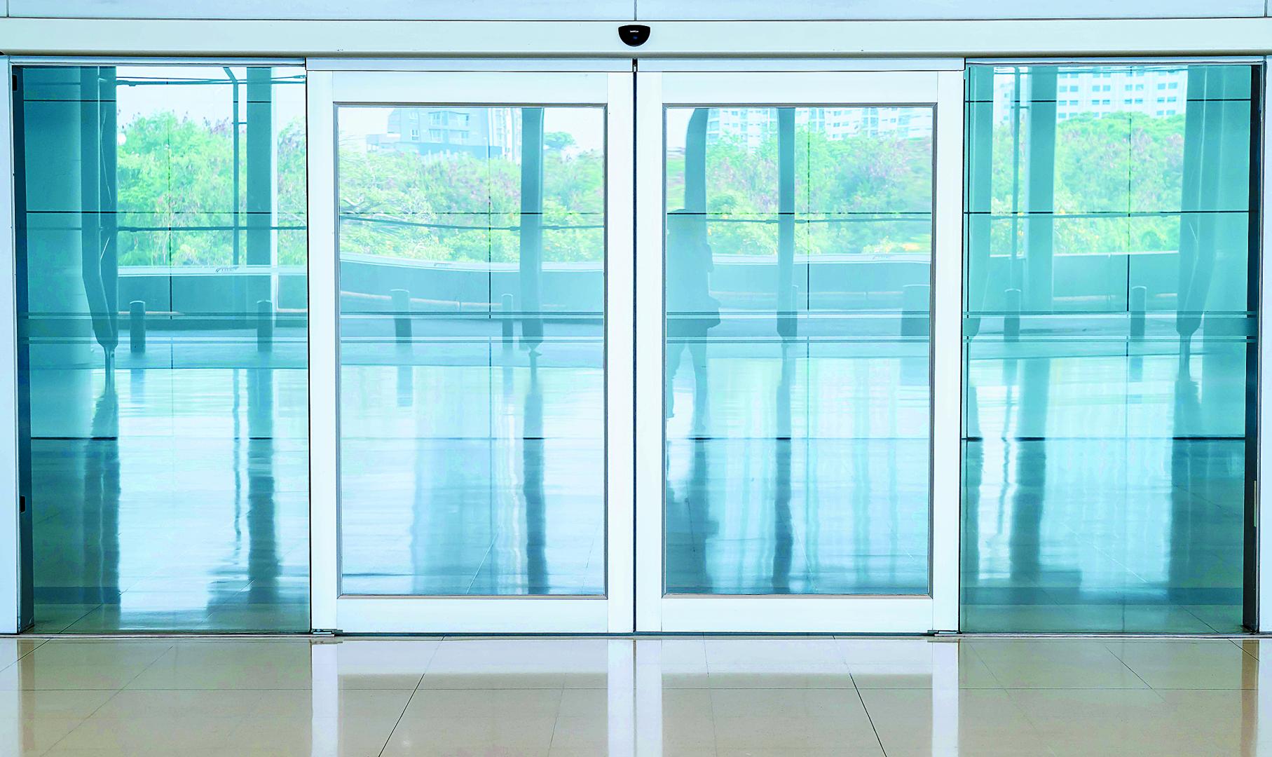 Imagen genérica de una puerta automática con dos paneles de cristal y un sensor que detecta la aproximación