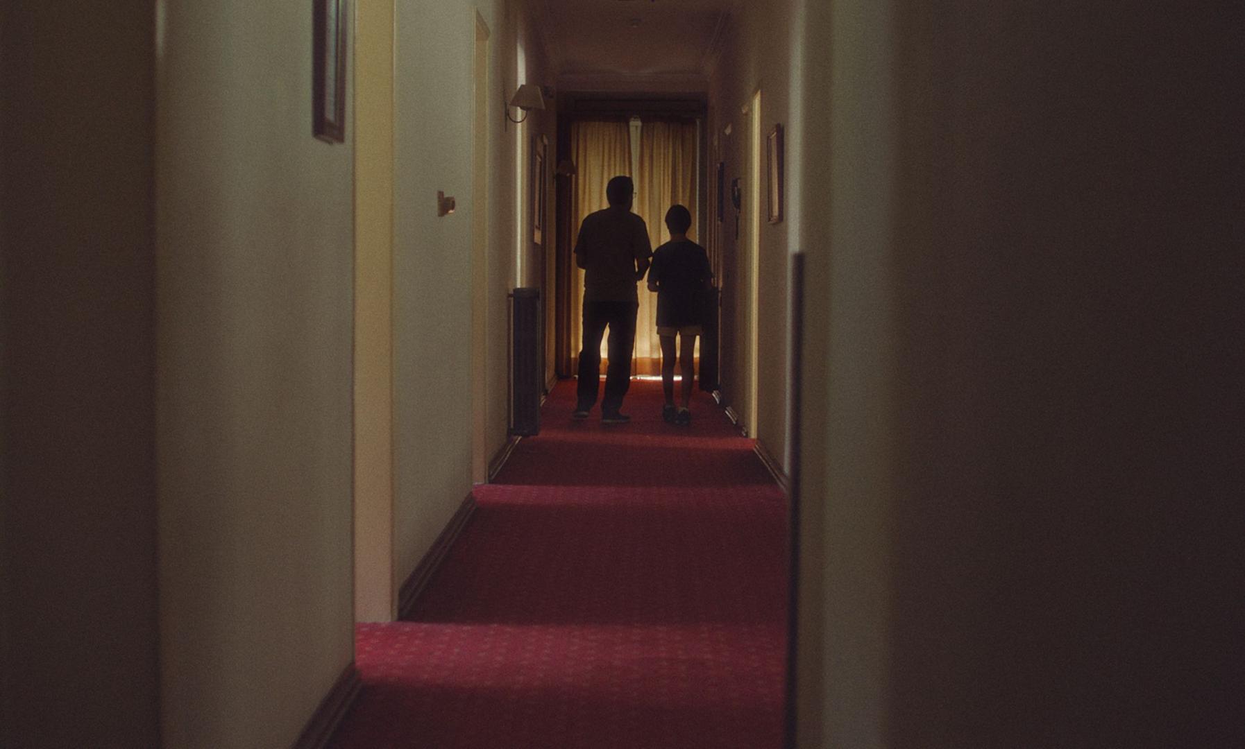 Fotograma de 'Una película de miedo' con padre e hijo por uno de los pasillos del hotel abandonado