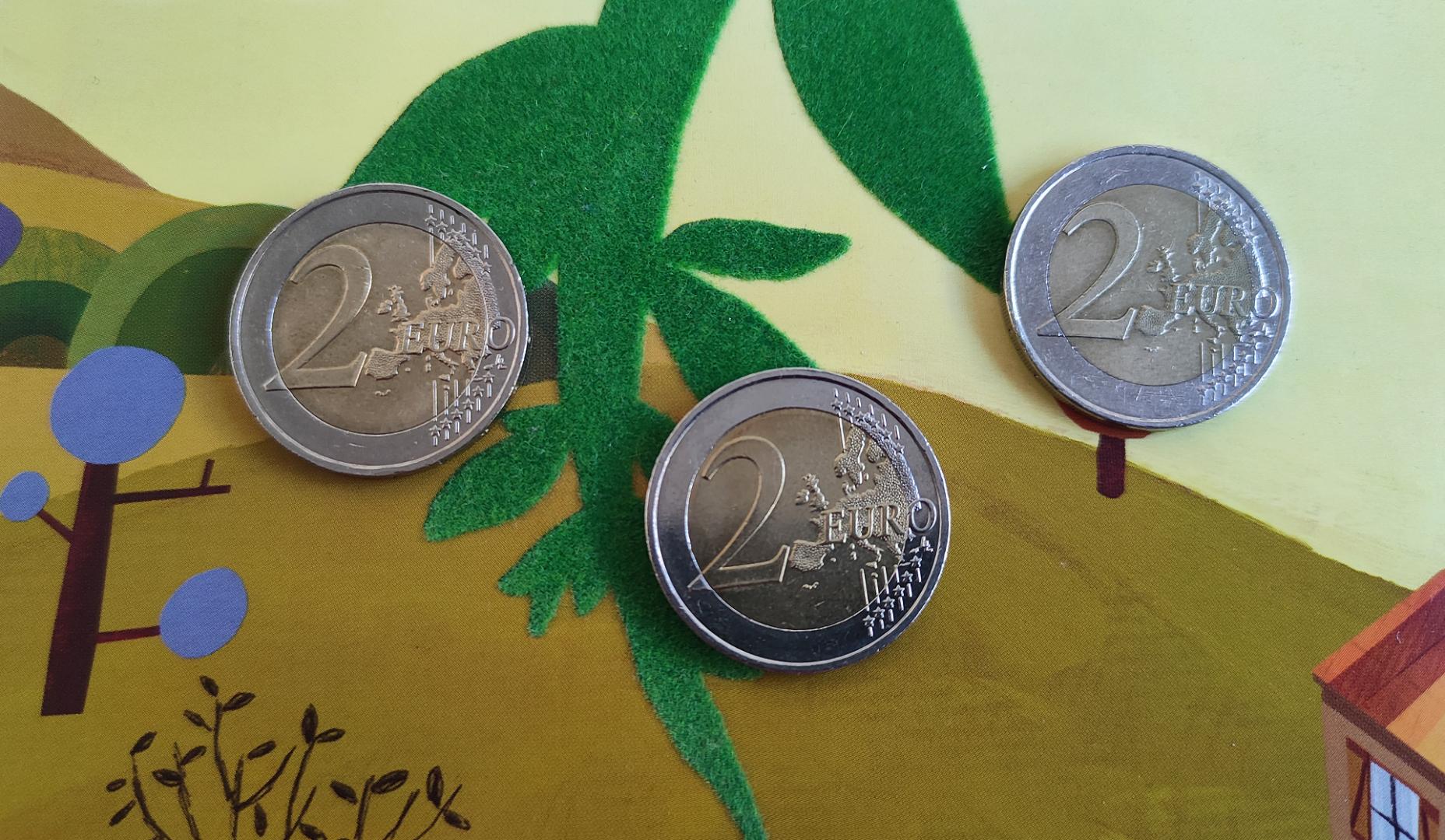 Tres monedas de 2 euros sobre un cuento infantil