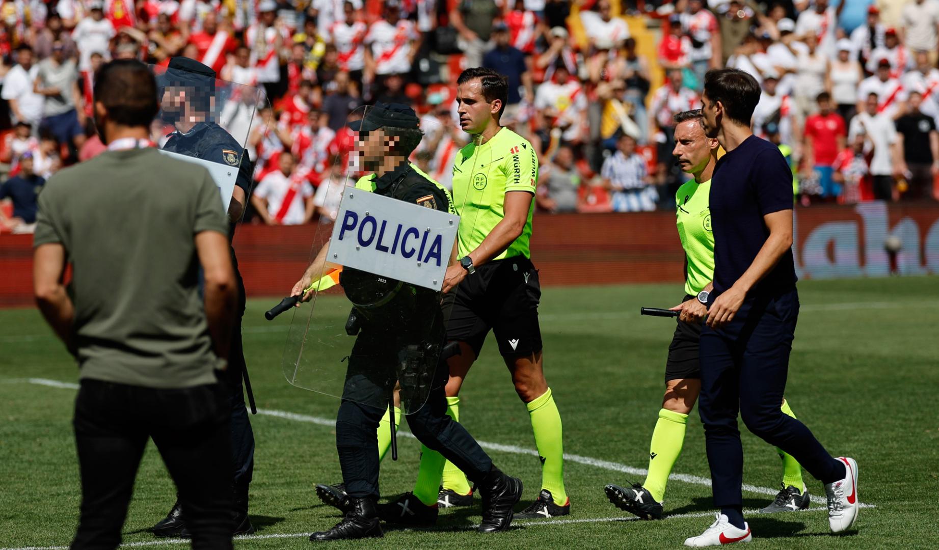 El arbitro José Luis Guzmán Mansilla (c) sale escoltado por la policiía mientras escucha las quejas del entrenador del Rayo Vallecano Íñigo Pérez (d) tras el partido de LaLiga entre el Rayo Vallecano y la Real Sociedad
