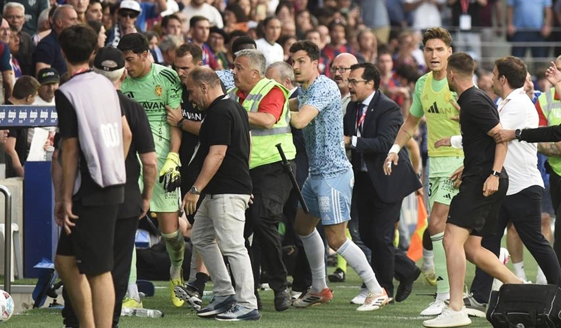 Los compañeros retiran al meta de Zaragoza, Andrada (izda.) tras la agresión a Pulido