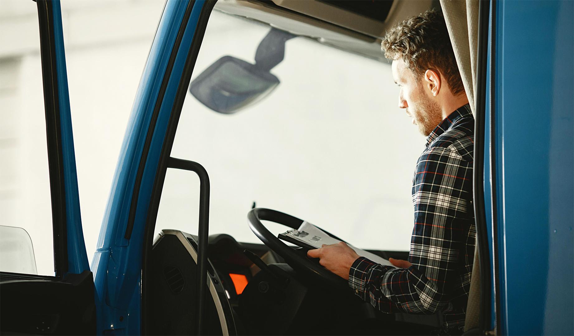 Un camionero consulta documentación a bordo de la cabina de su vehículo